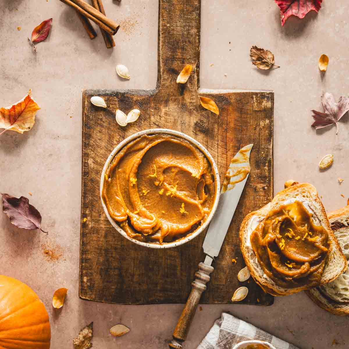 bowl with pumpkin butter on a wooden board, slices of bread, knife,