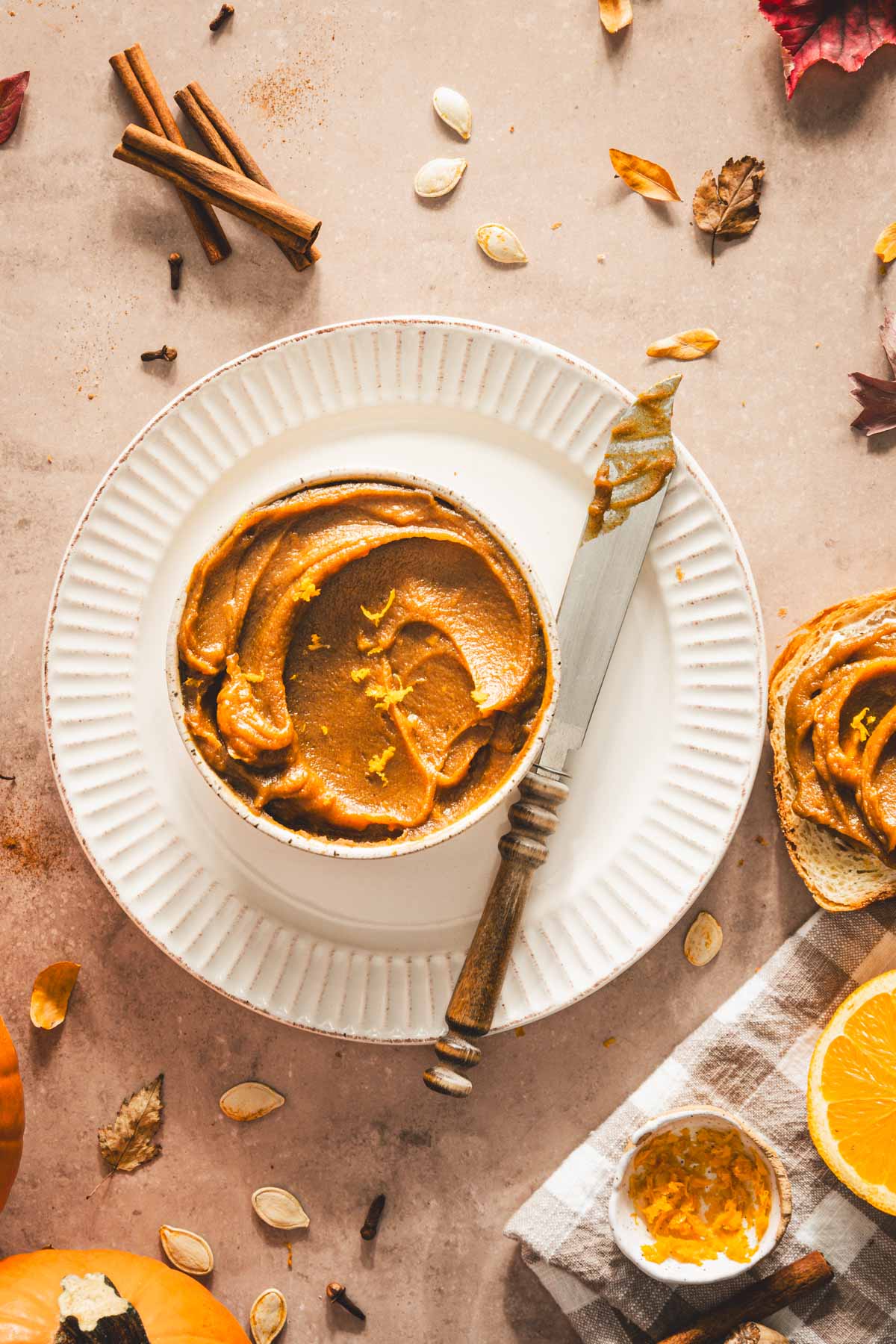 pumpkin butter in a serving bowl displayed on a plate with knife