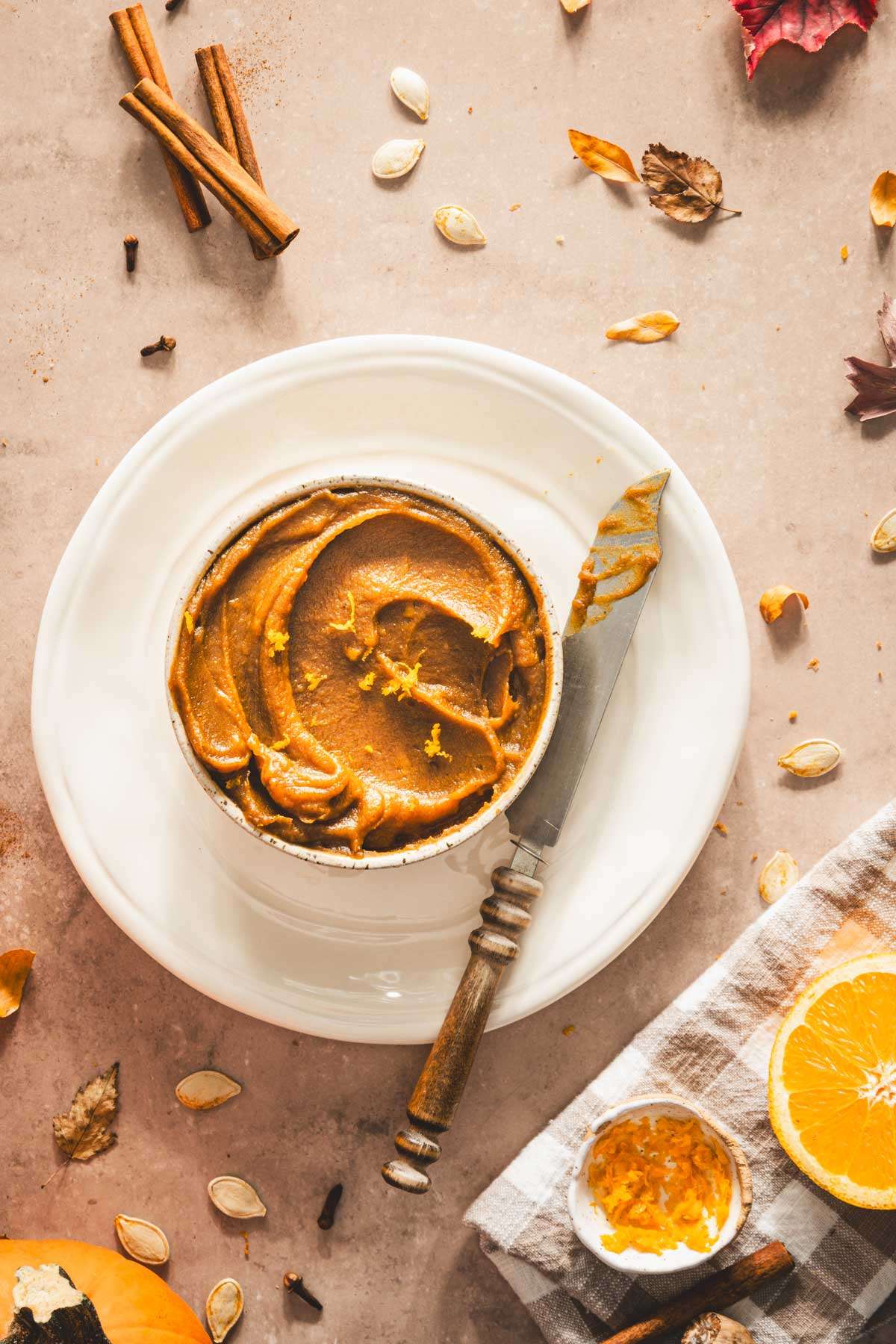 pumpkin butter in a serving bowl displayed on a plate with knife