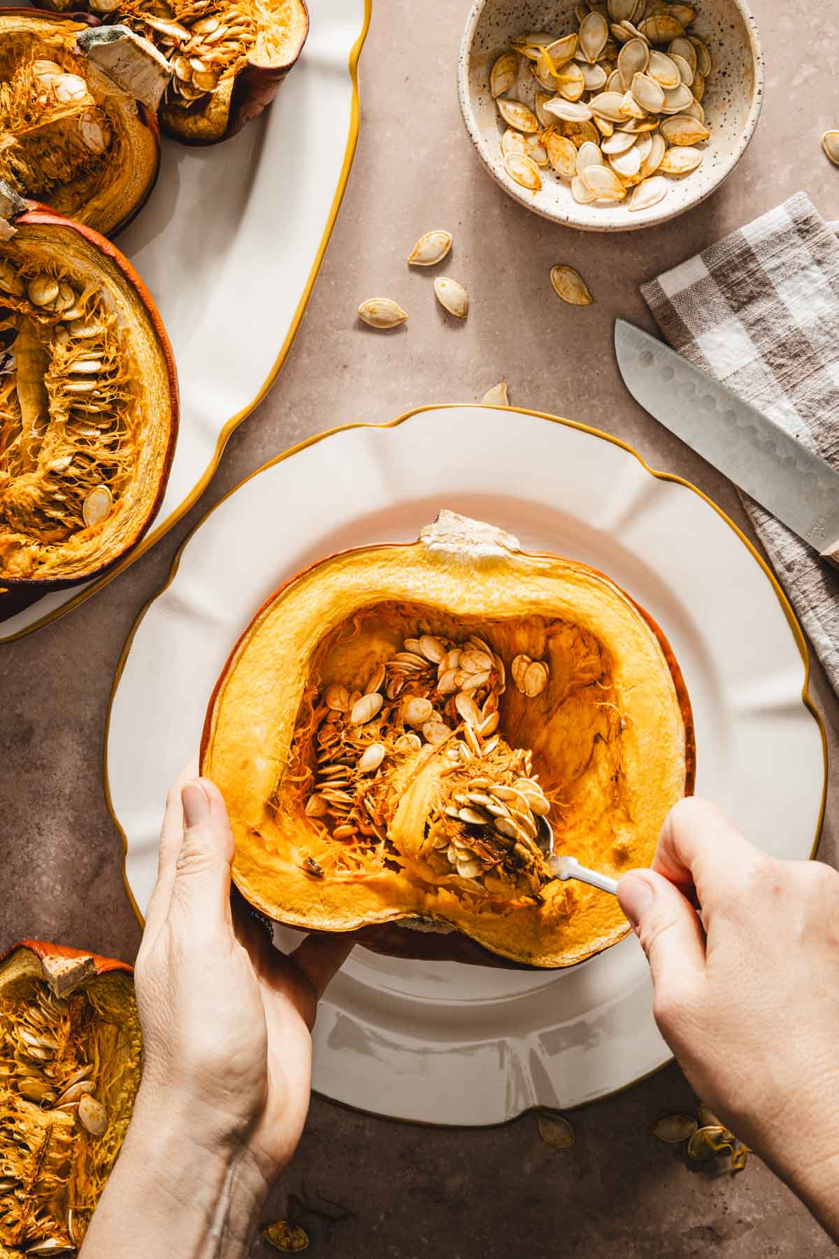 hands in frame scooping pumpkin flesh