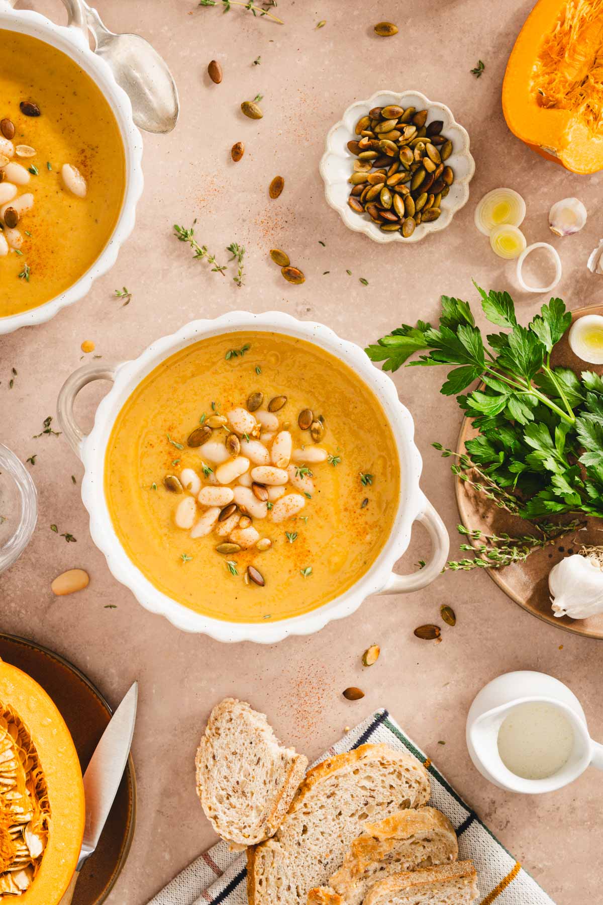 pumpkin soup in serving bowls, fresh parsley, cut up pumpkin, bread slices