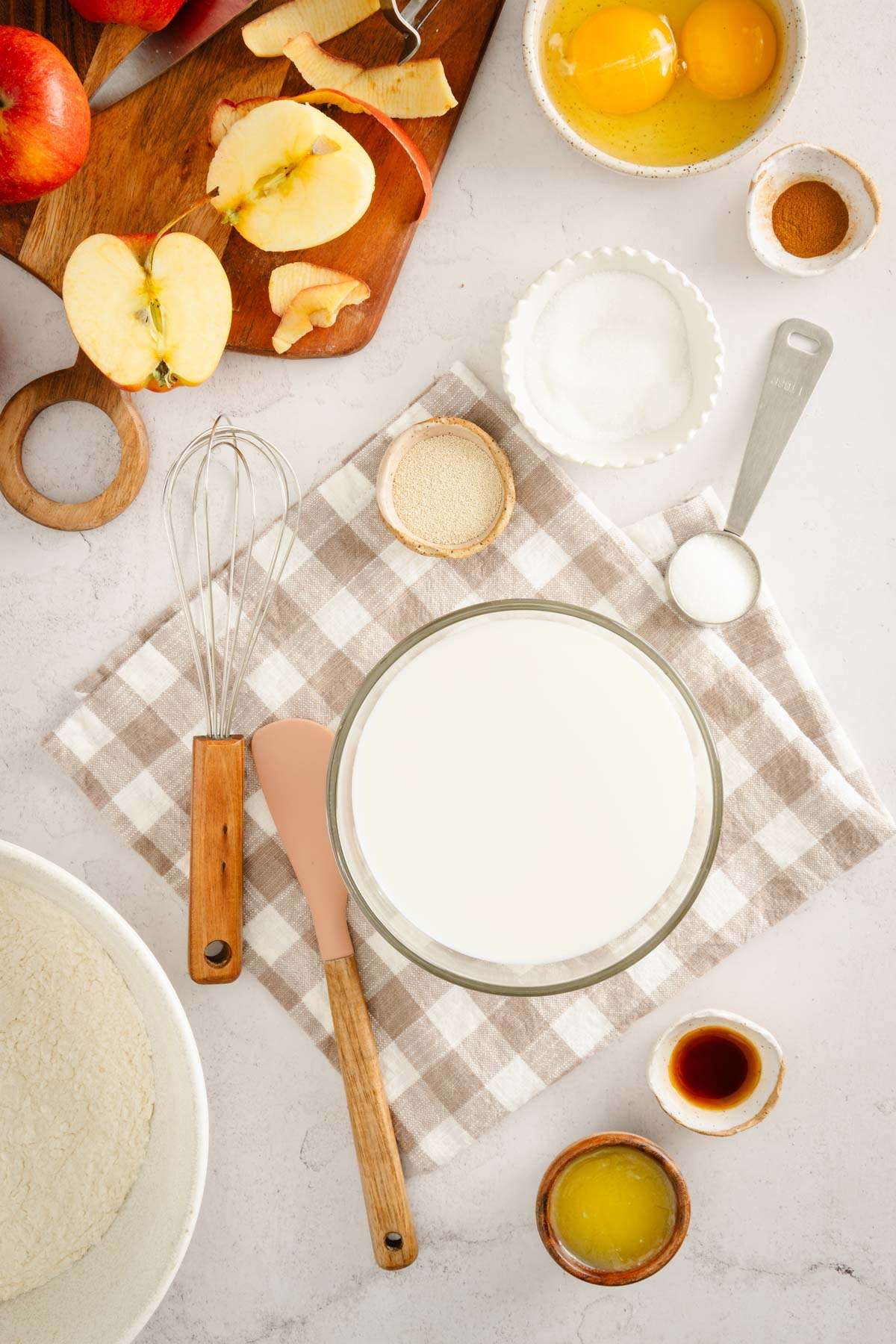 bowl with milk, yeast, sugar and other ingredients around