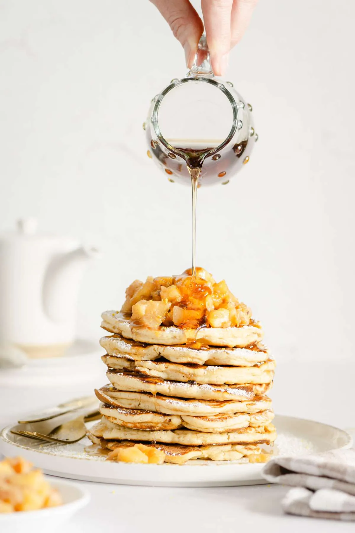 hand in frame pouring syrup over stack of racuchy
