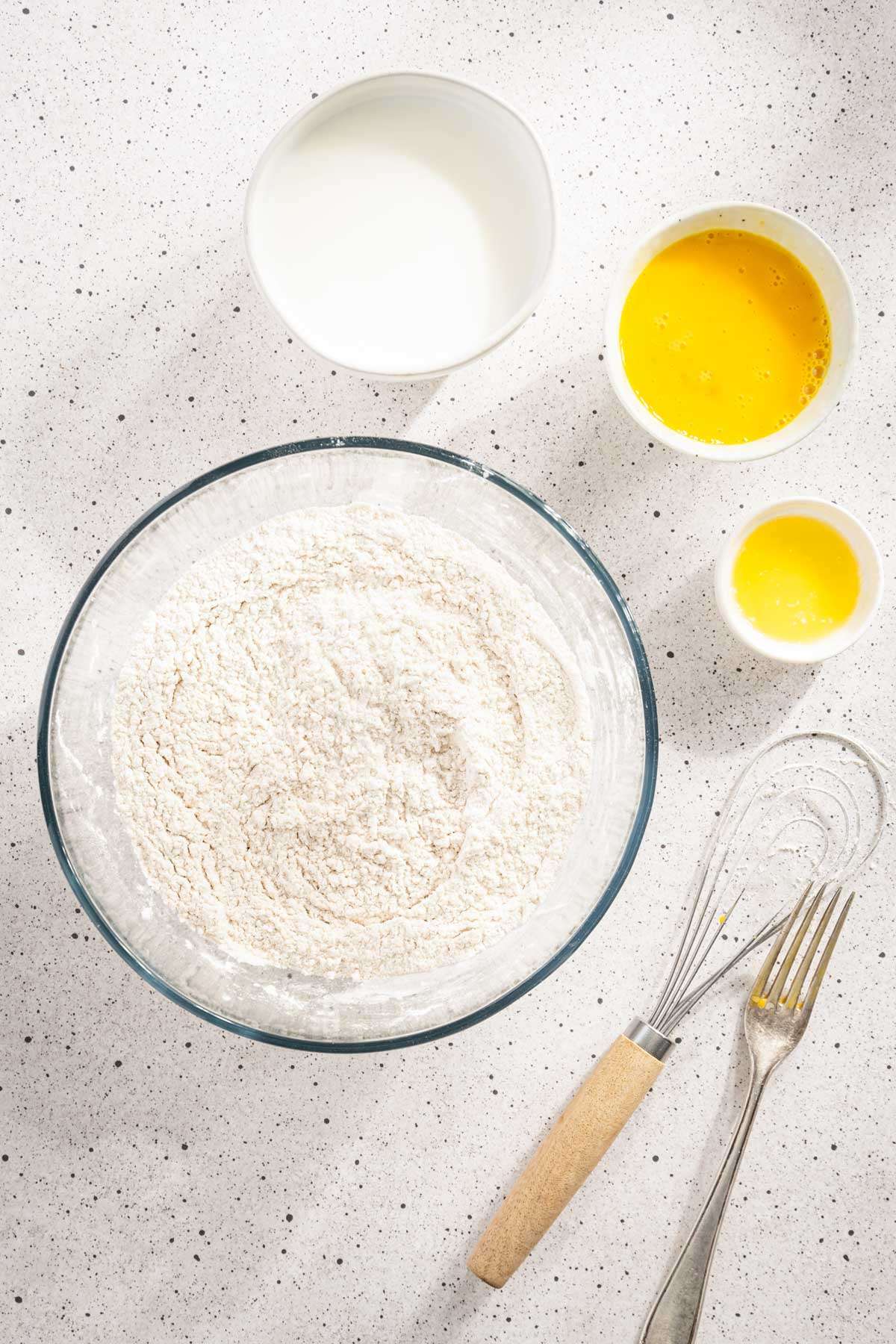 Flour in a glass bowl, other ingredients to make Racuchy around