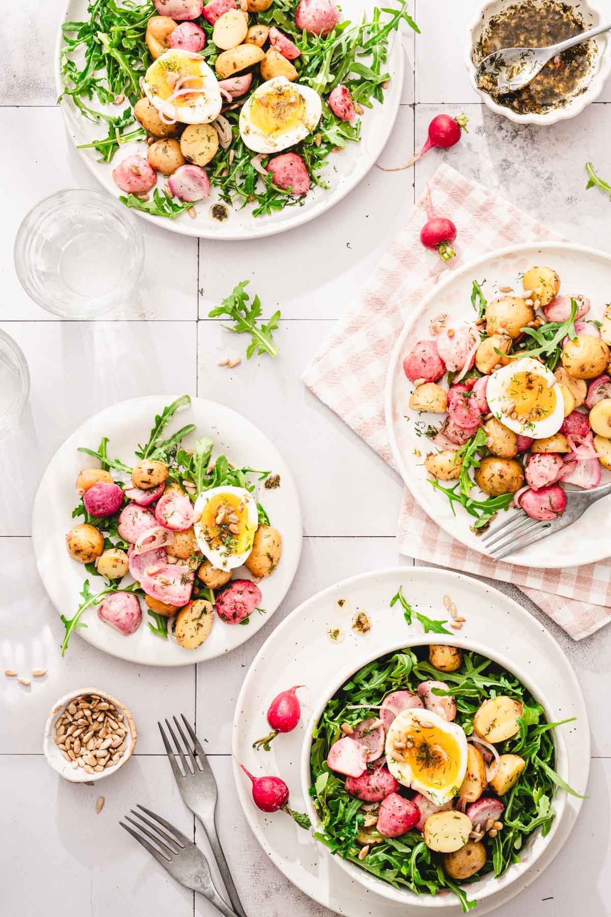 various plates with the salad, forks, dish with dressing