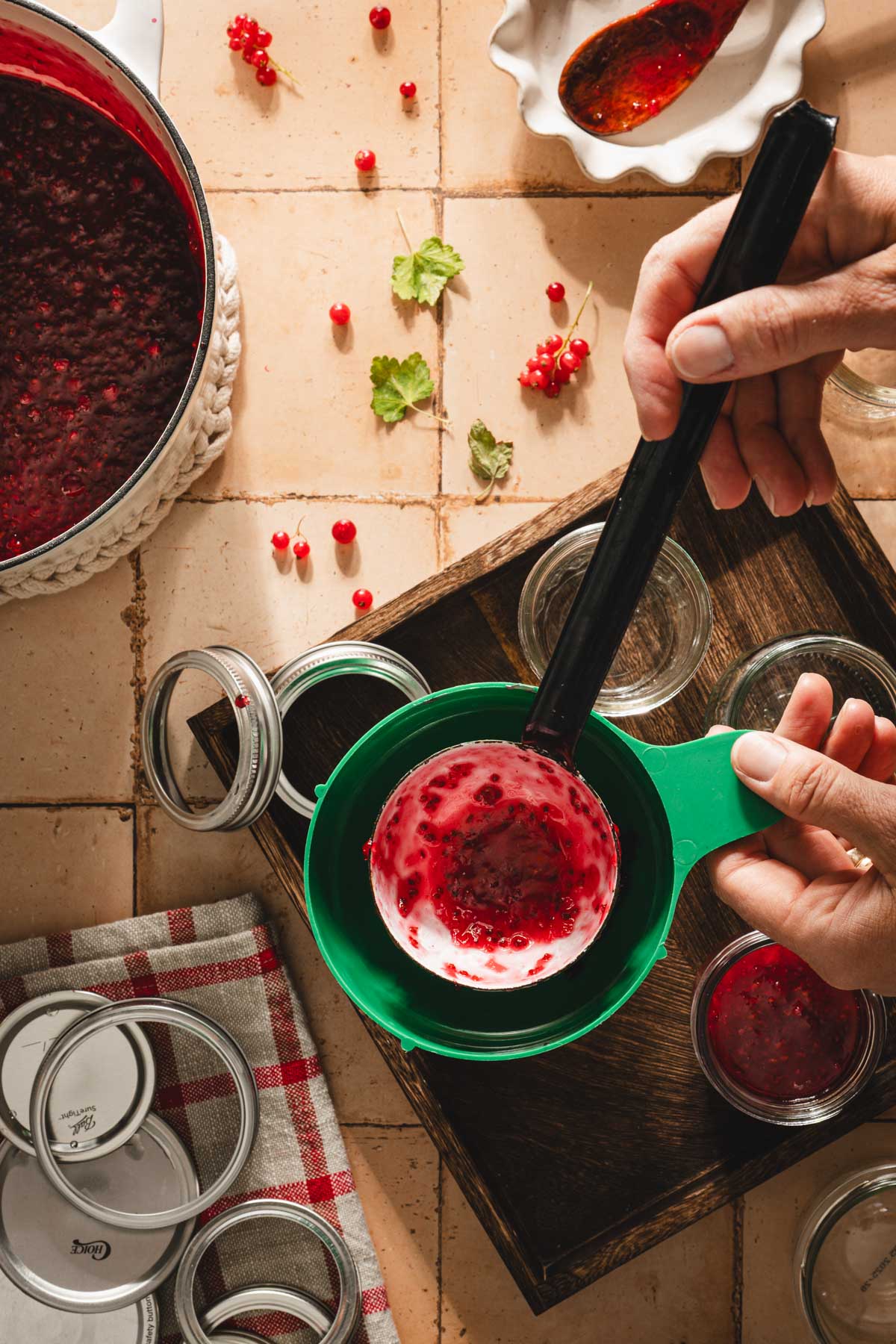 hands in frame holding ladle over jar with jam