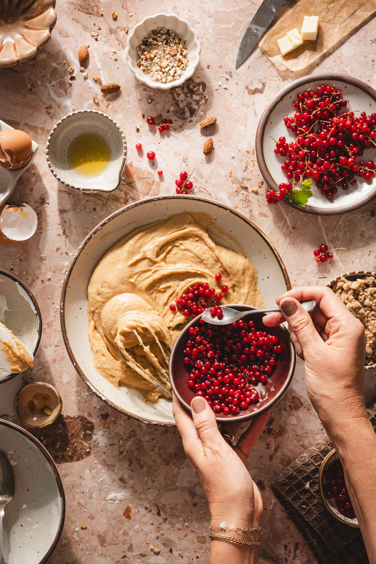 hands in frame adding currants to the cake batter