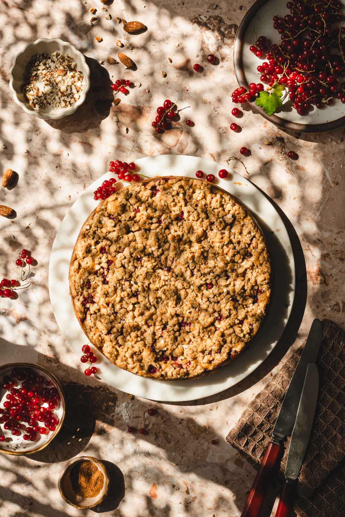 baked cake on a serving platter, little bowl with berries, plate with berries
