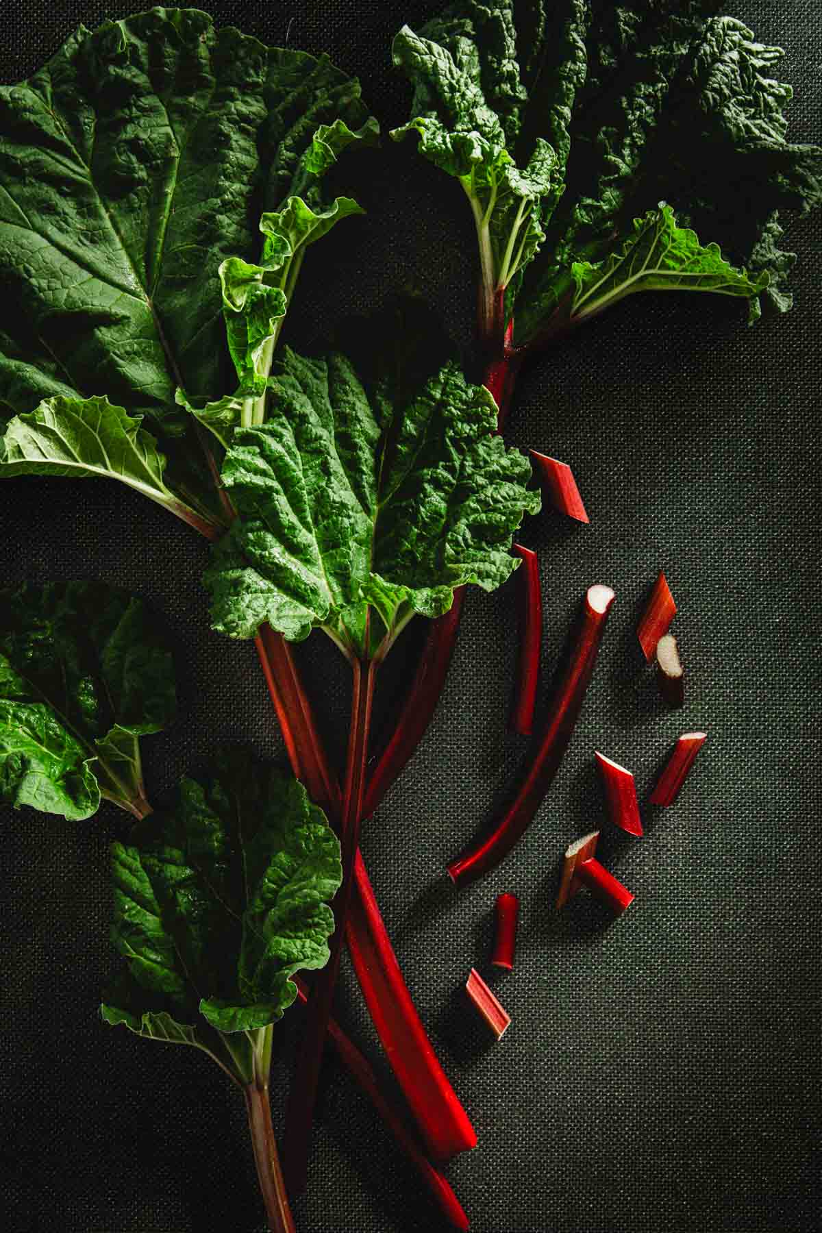 rhubarb stalks with leaves, few cut up rhubarb pieces