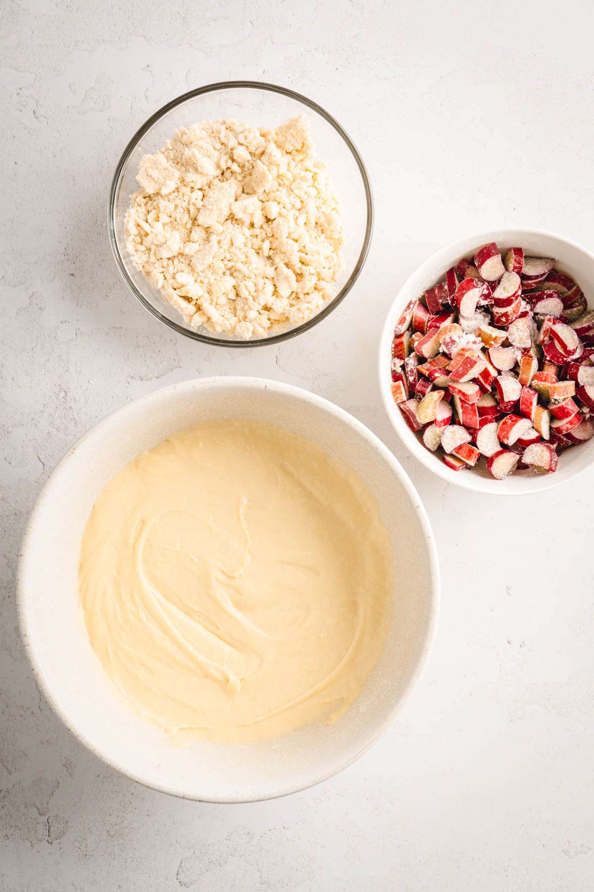 bowls, one with batter, one with cut up rhubarb, and one with crumble