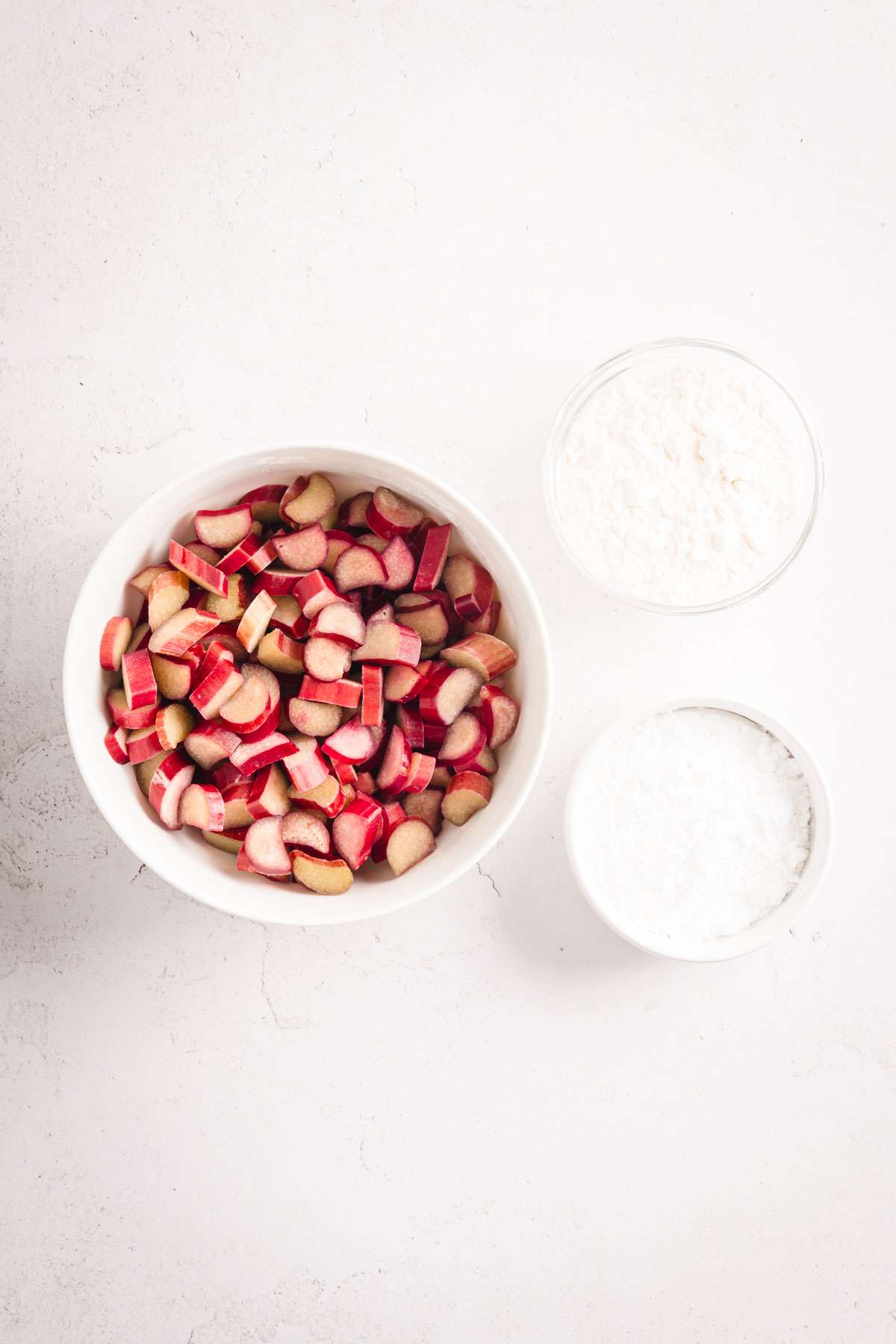 bowl with cup up rhubarb, dish with flour and one with powdered sugar