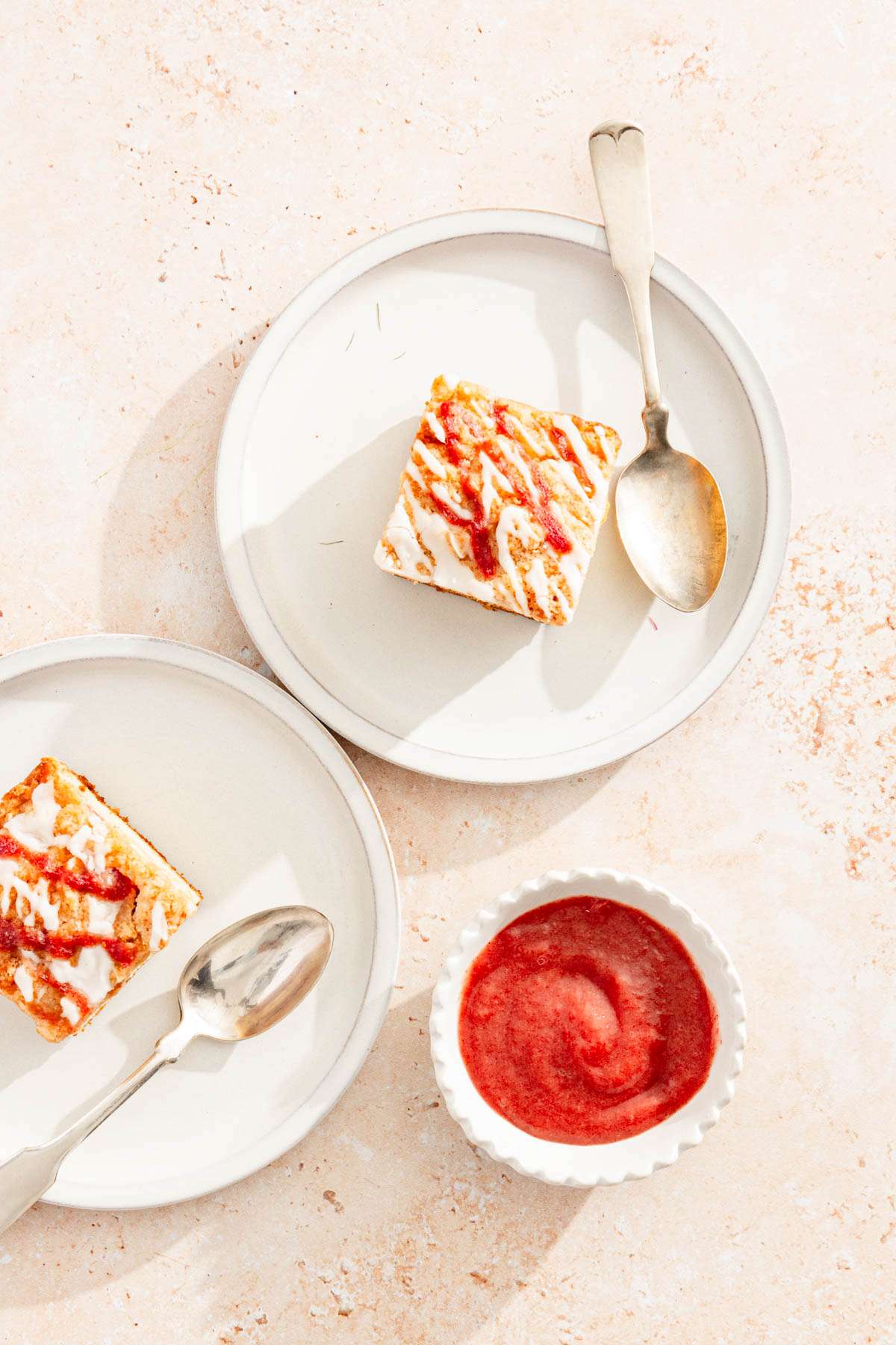 top view, slices of rhubarb cake on plates, spoons and a dish with rhubarb butter