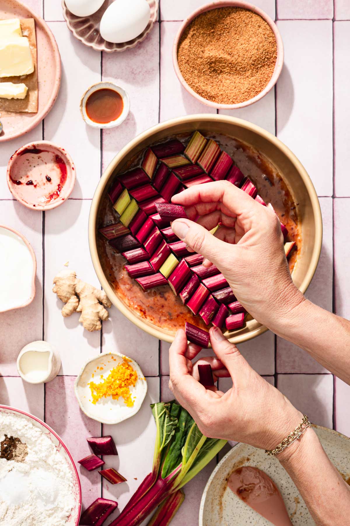 hands inm frame adding rhubarb pieces to the baking pan