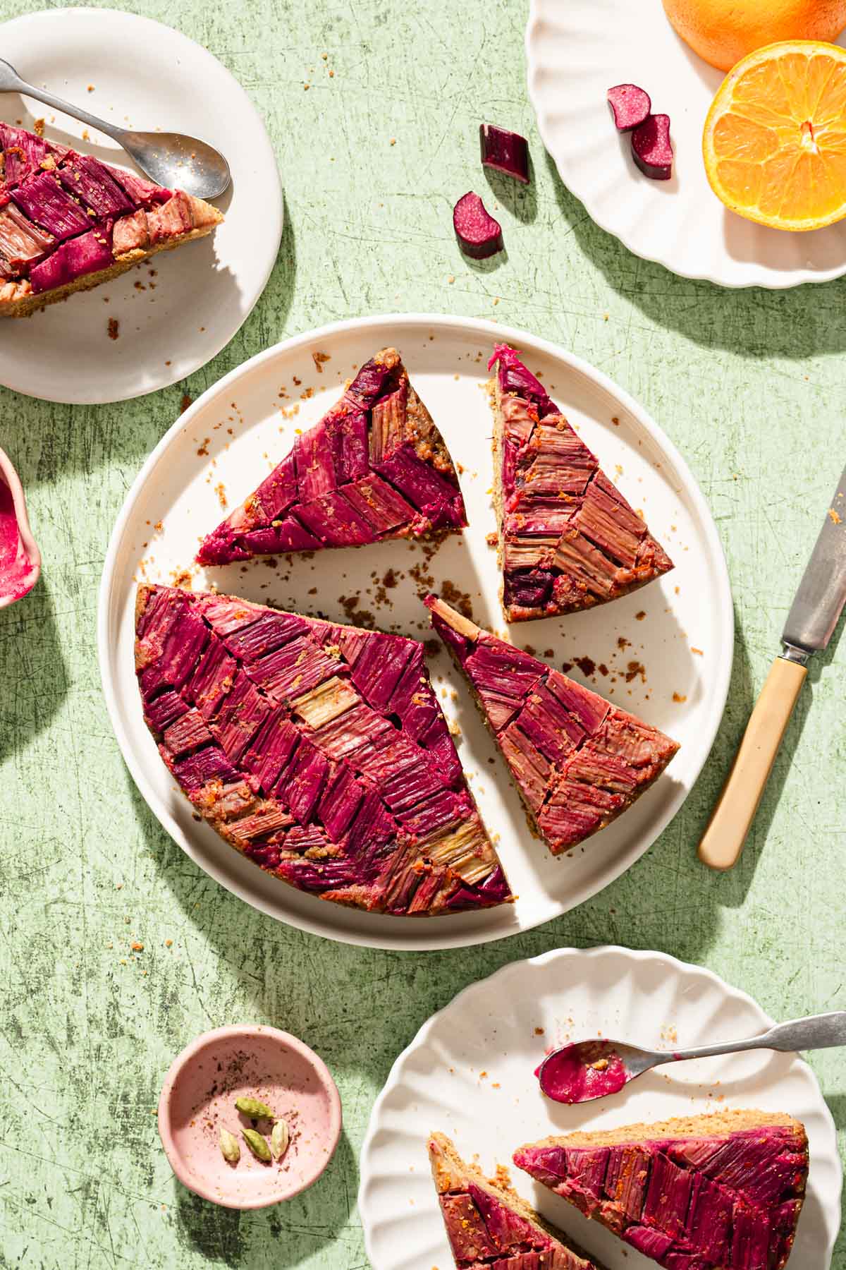 various plates with rhubarb cake, green backdrop