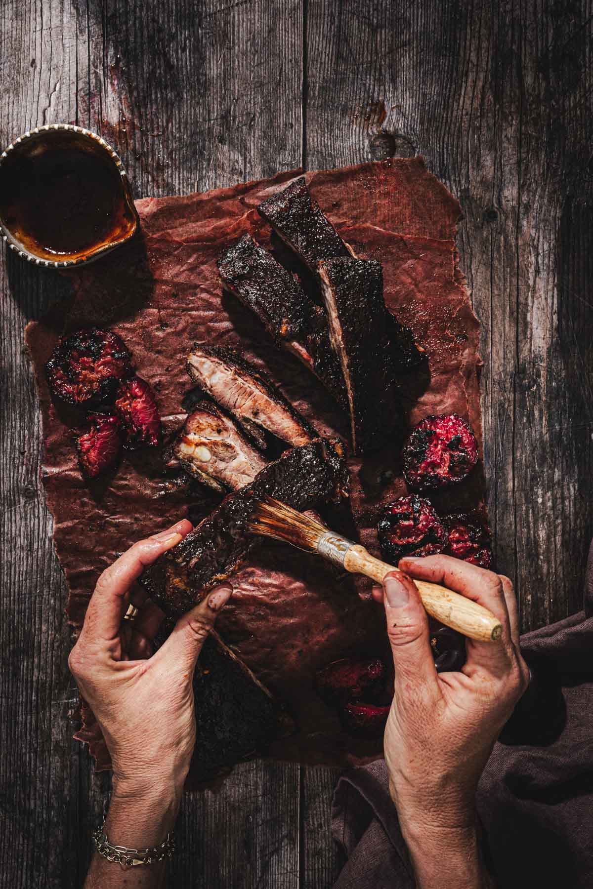 hands in frame holding a brush with bbq sauce