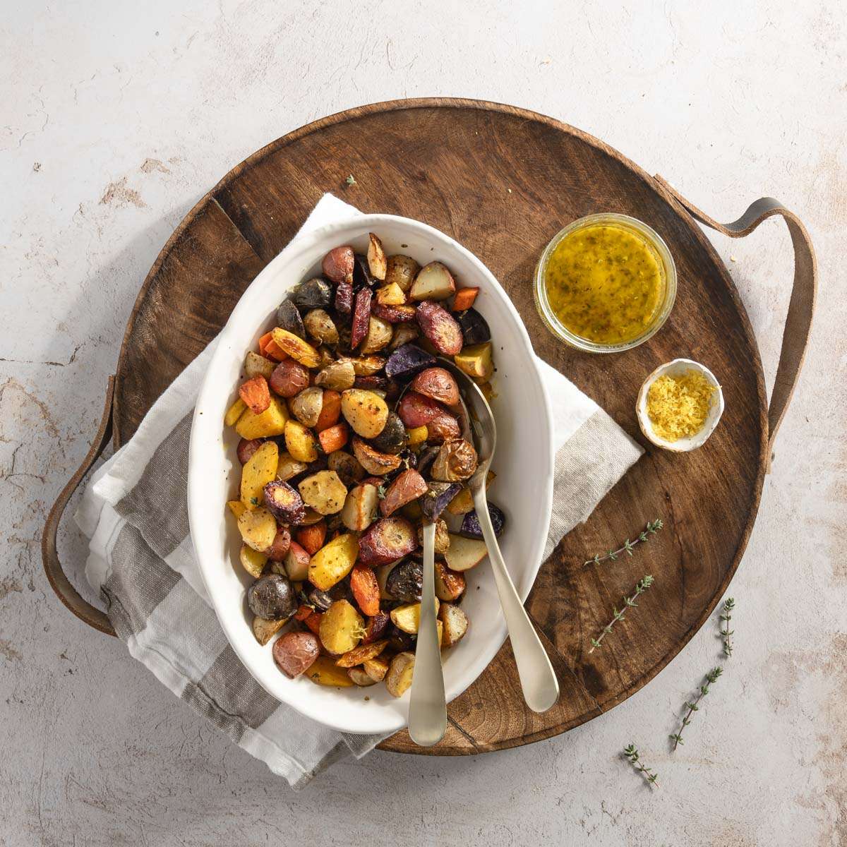 roasted veggies on a serving platter, dish with vinaigrette and other with lemon zest