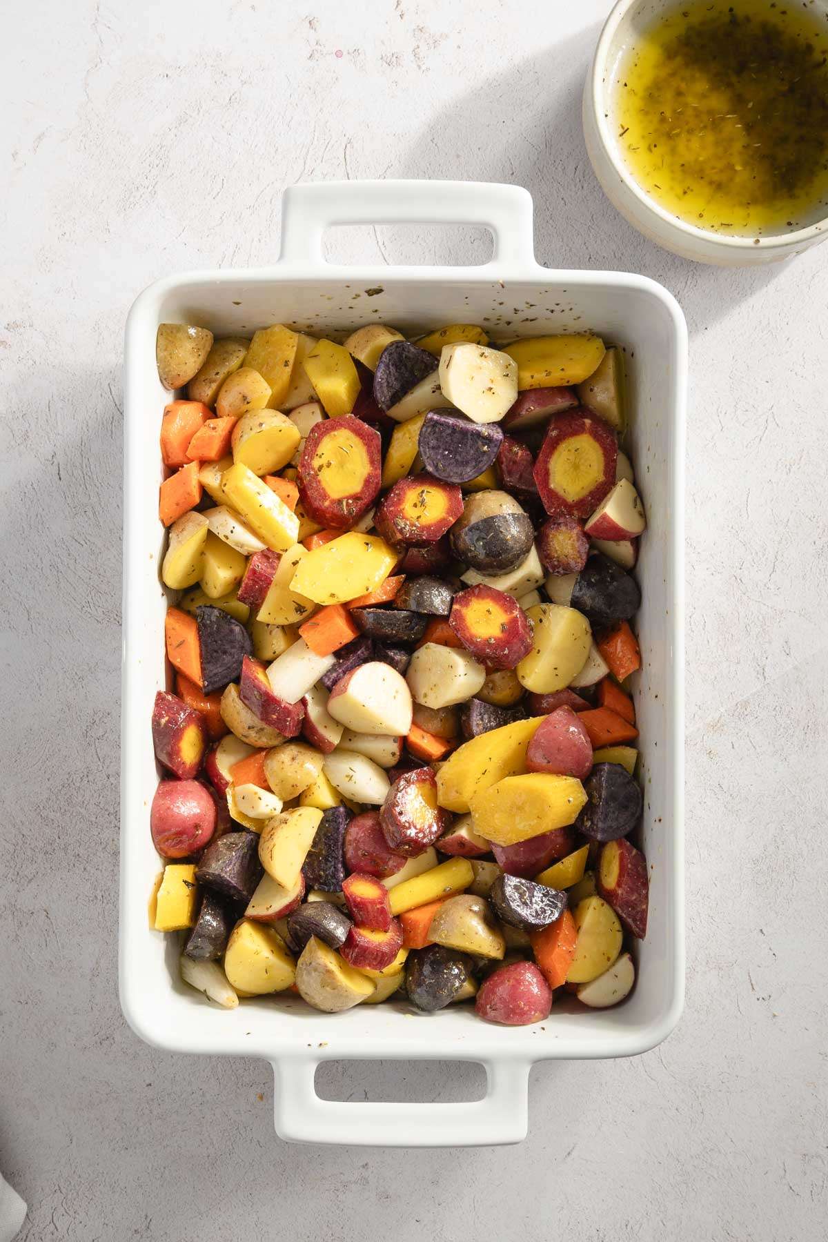 variety of vegetables, cut into up and placed in a baking deep dish; upper right corner small bowl with vinaigrette