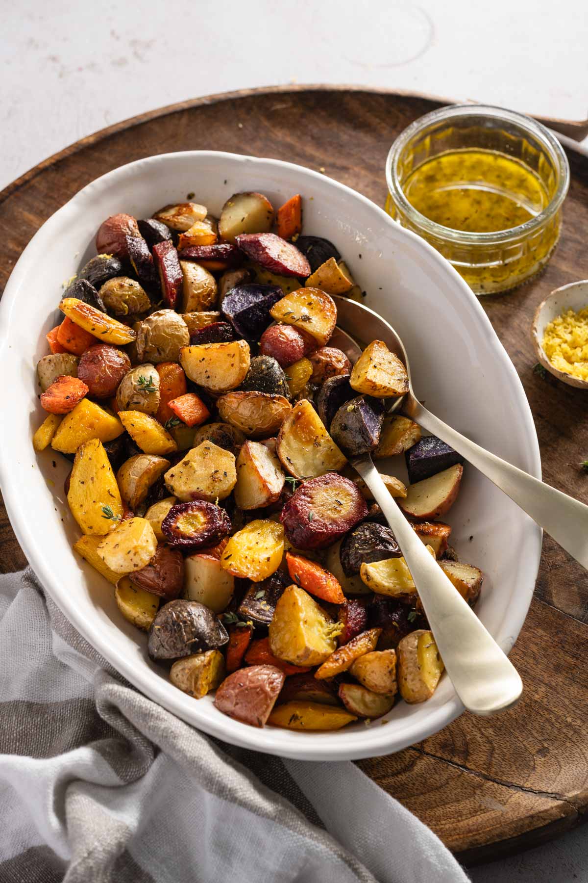 Roasted Vegetables in a glass dish, side of dressing and lemons zest