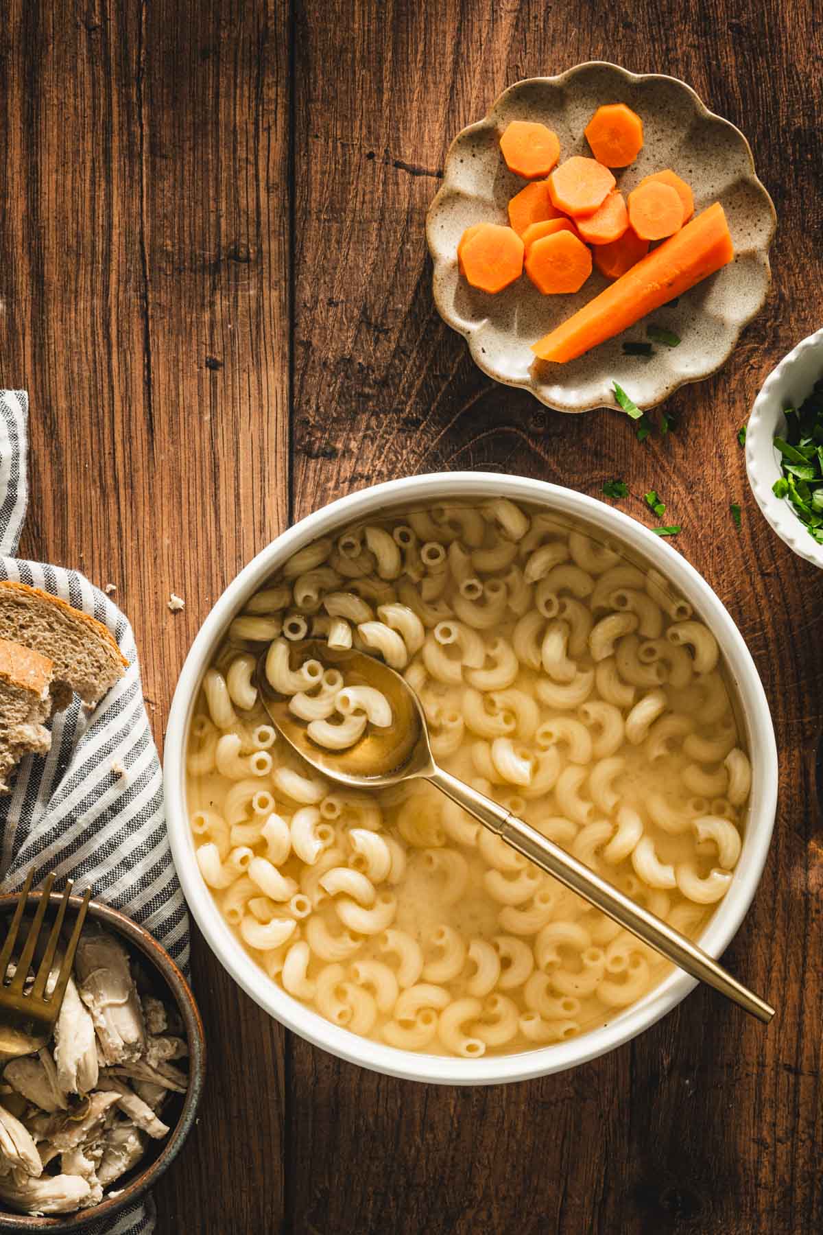 rosol in a serving bowl, sliced carrots on a small plate, parsley in a small bowl, shredded chicken on a plate