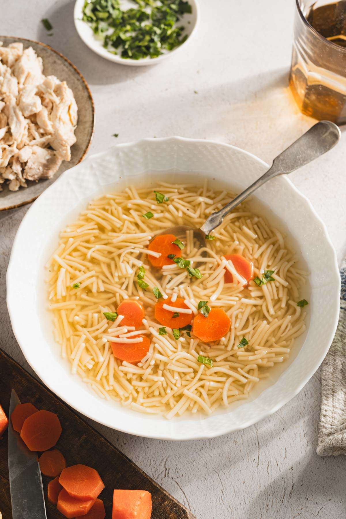 rosol in a serving bowl, sliced carrots, parsley, shredded chicken on a plate