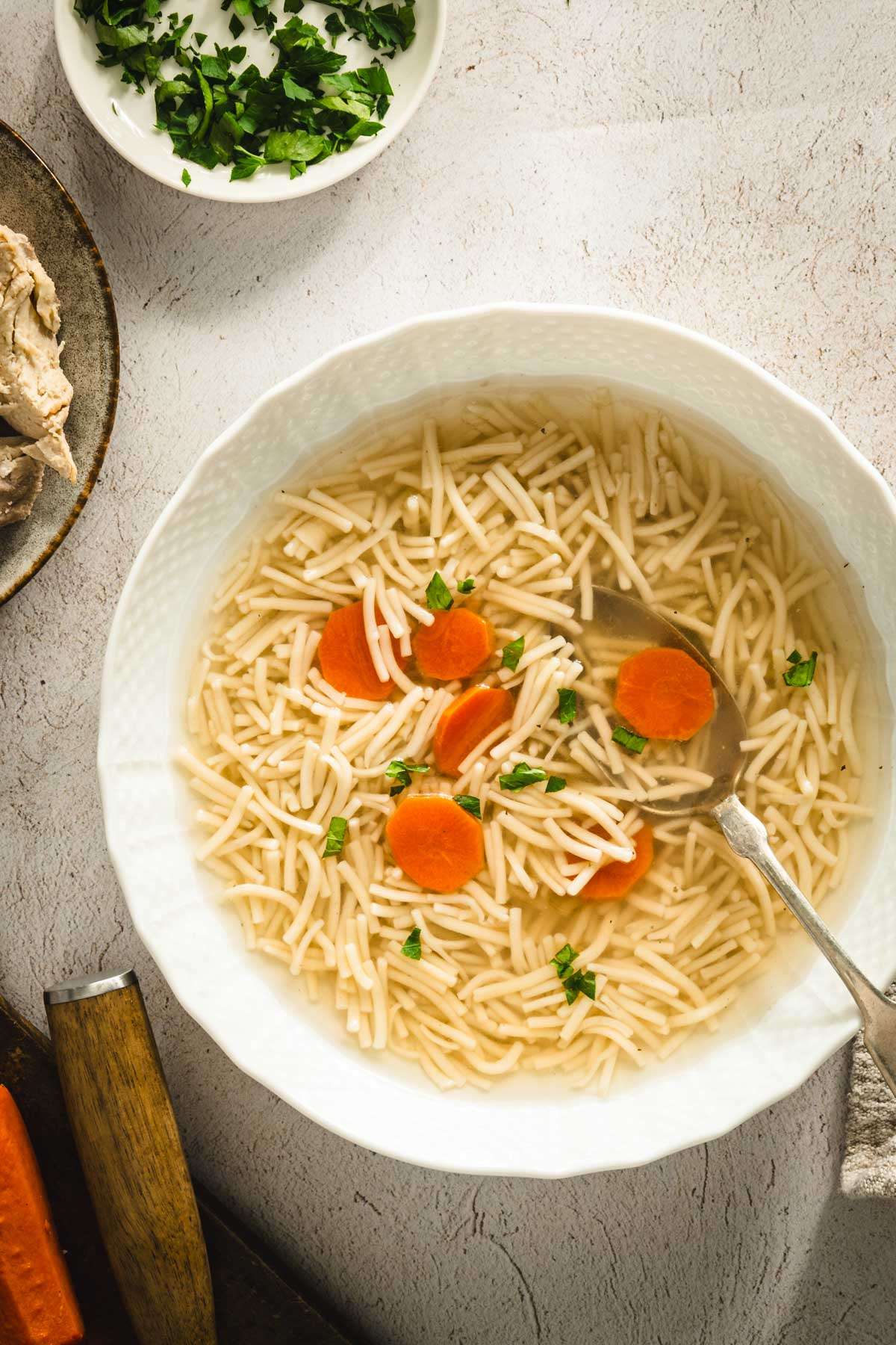 rosol in a serving bowl, sliced carrots, parsley, shredded chicken on a plate