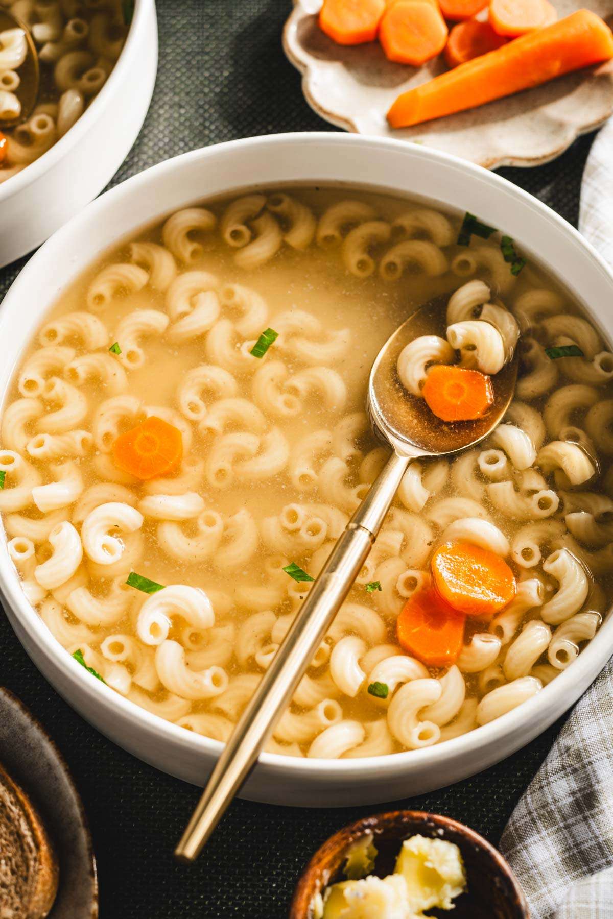 rosol in a serving bowl, sliced carrots on a small plate, parsley in a small bowl, shredded chicken on a plate