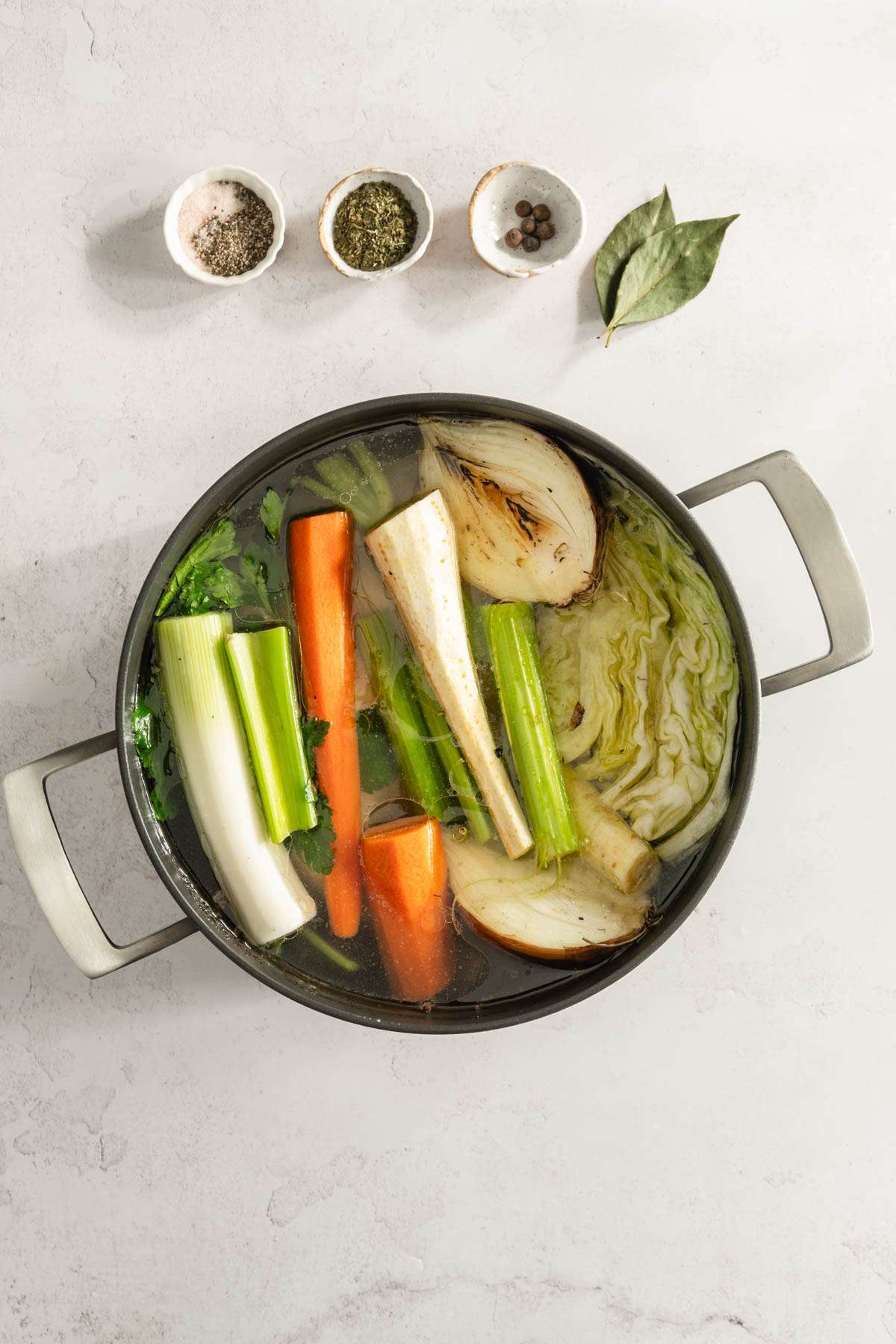 large cooking pot with chicken and veggies, small dishes with spices