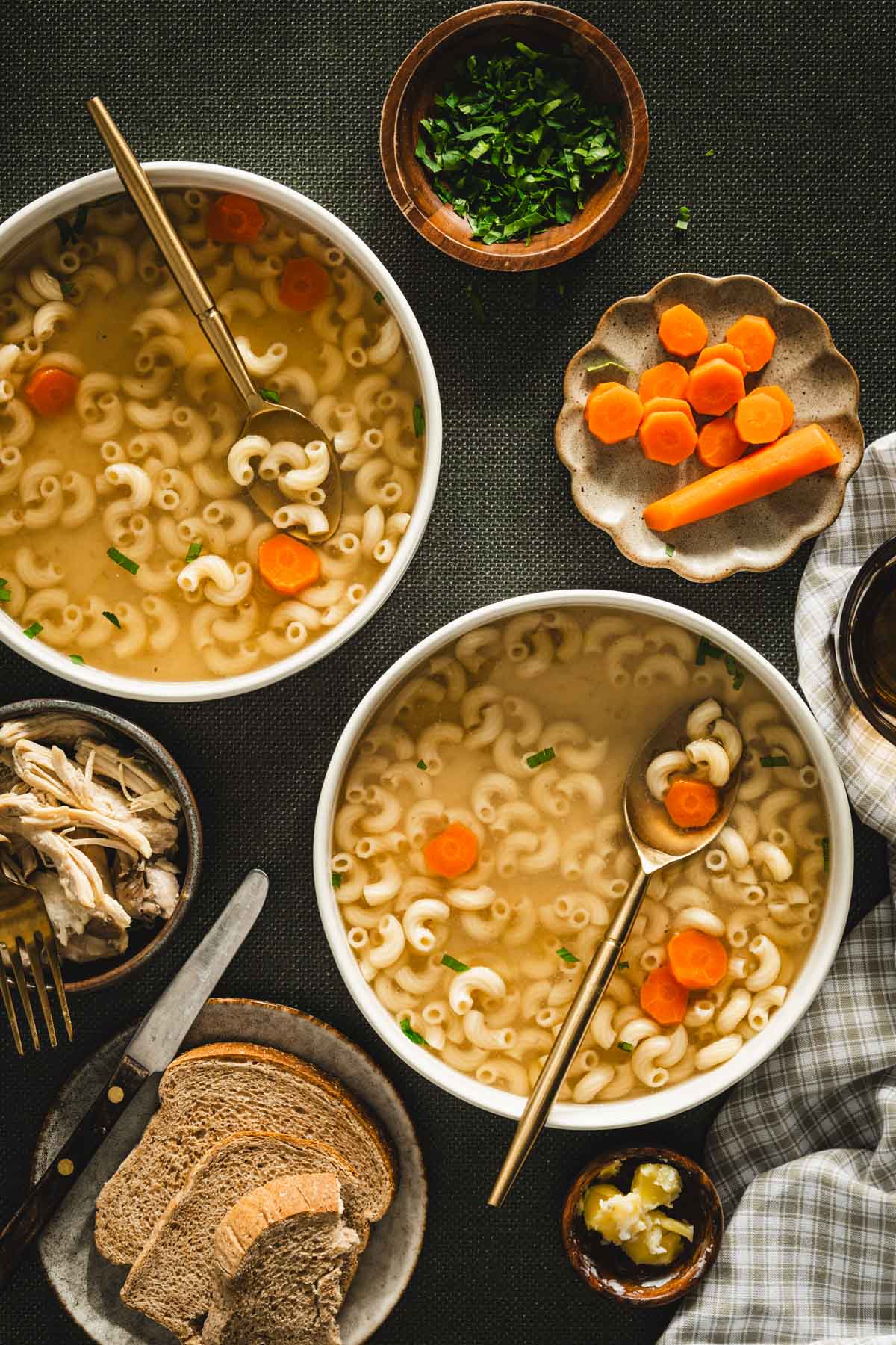 rosol in a serving bowl, sliced carrots on a small plate, parsley in a small bowl, shredded chicken on a plate