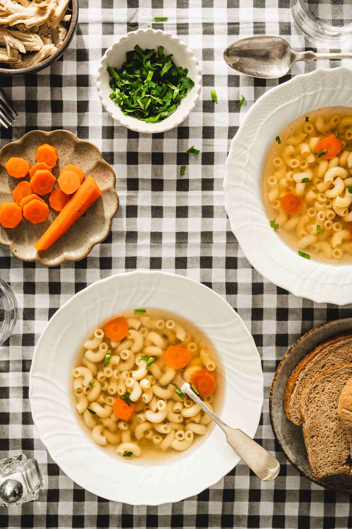 table set up, soup plates with rosol, small dish with carrots, bread in a basket, plate with shredded chicken