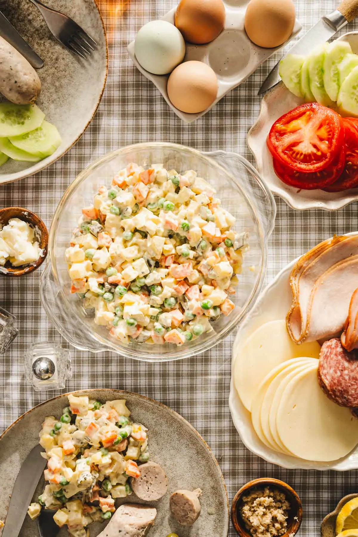 veggie salad in a glass bowl, breakfast table set up; cold cuts, kilebasa, slat,pepper, etc, sliced tomatoes and cucumbers, eggs
