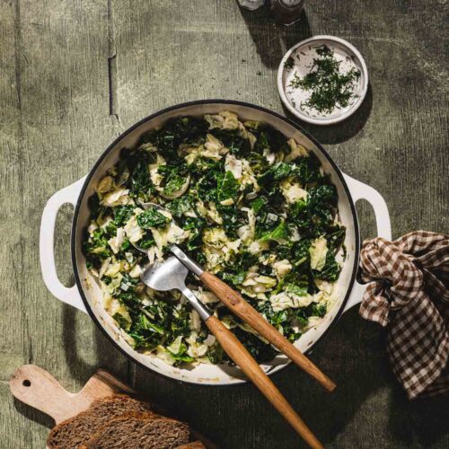 savory cabbage in a skillet with serving utensils