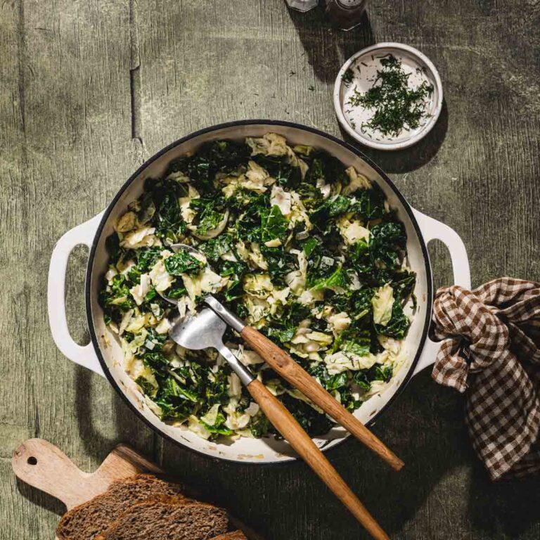 savory cabbage in a skillet with serving utensils