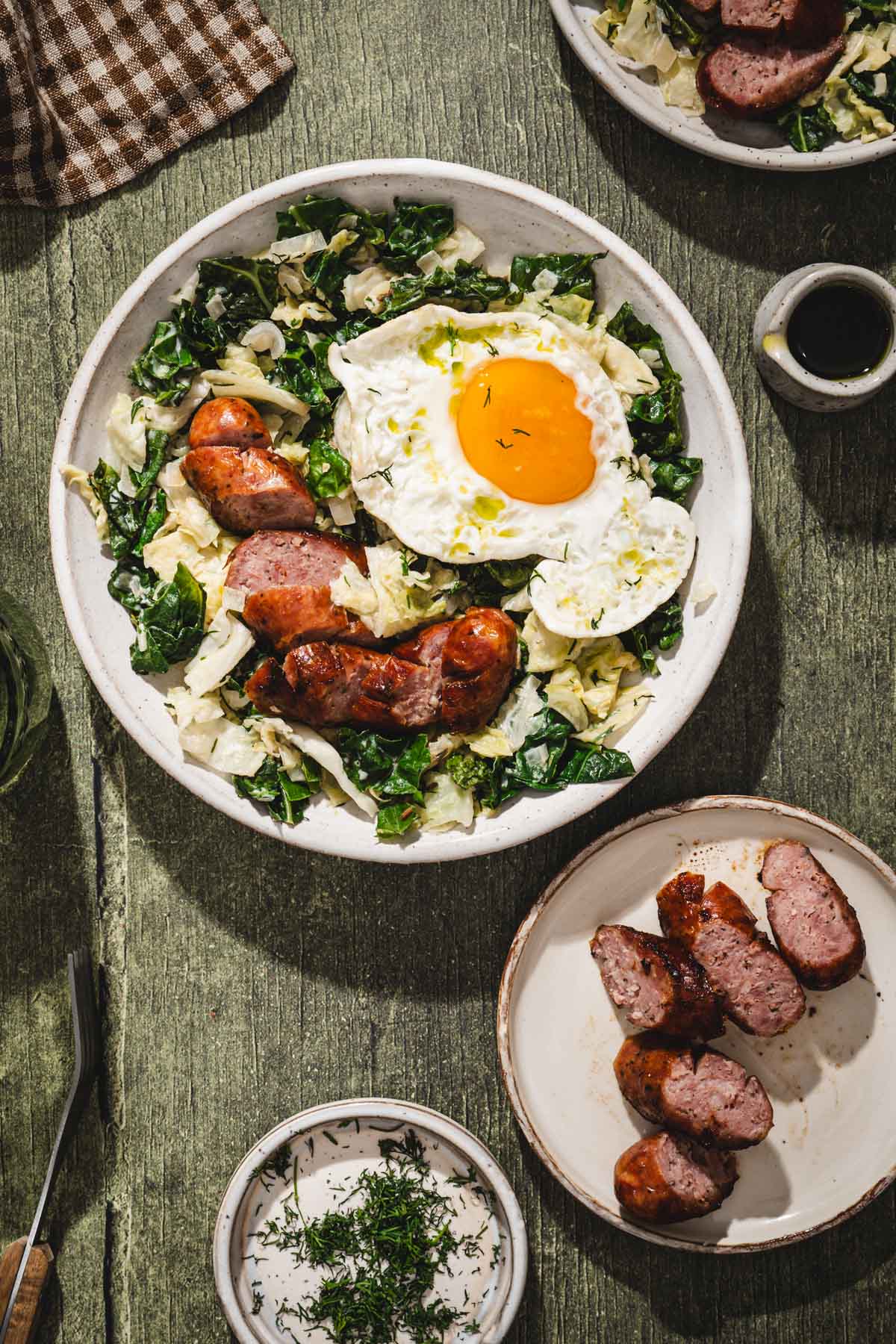 cabbage in a serving bowl, sunny side egg added, sliced sausage