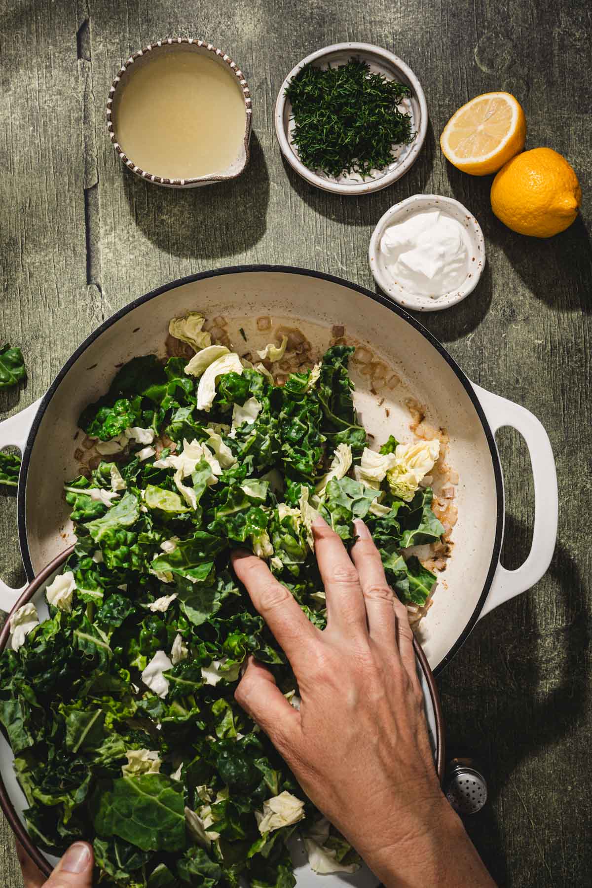 hands in frame adding cabbage to the skillet