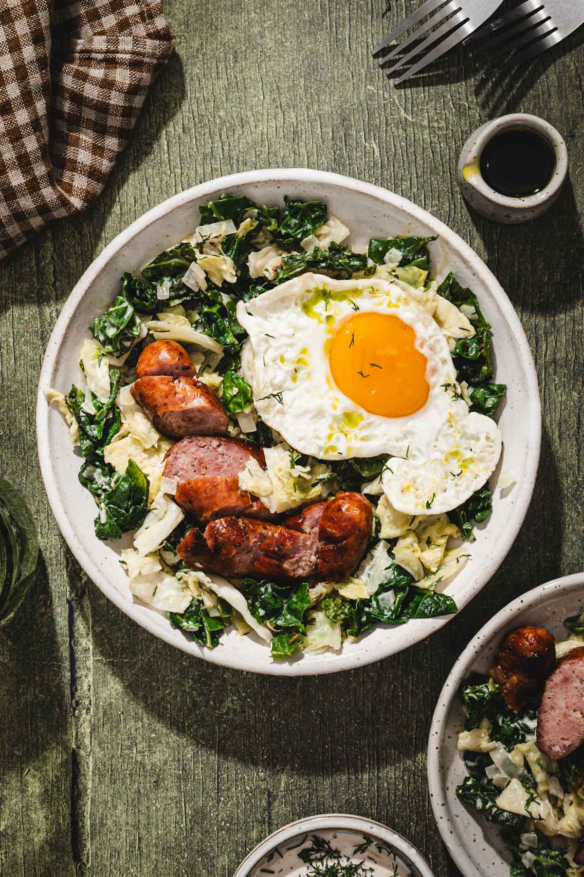 cabbage in a serving bowl, sunny side egg added, sliced sausage