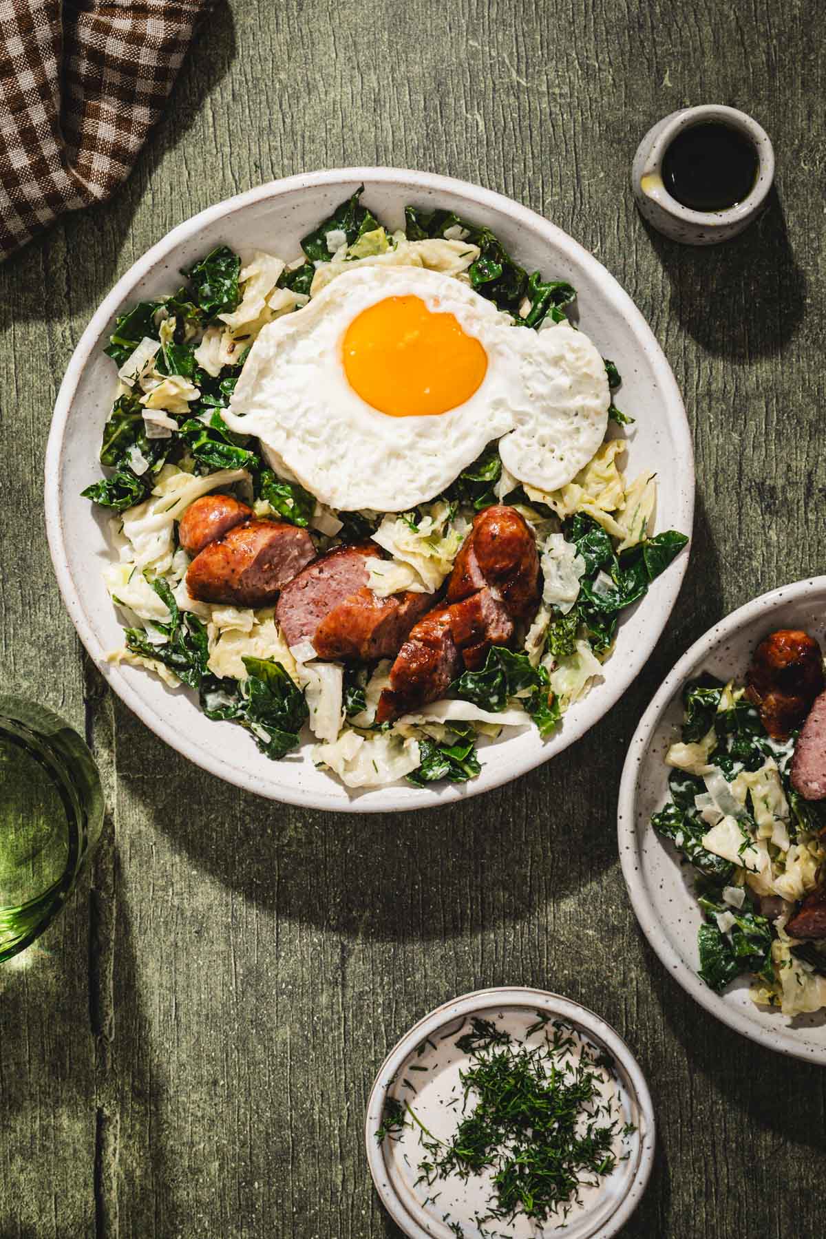 cabbage in a serving bowl, sunny side egg added, sliced sausage