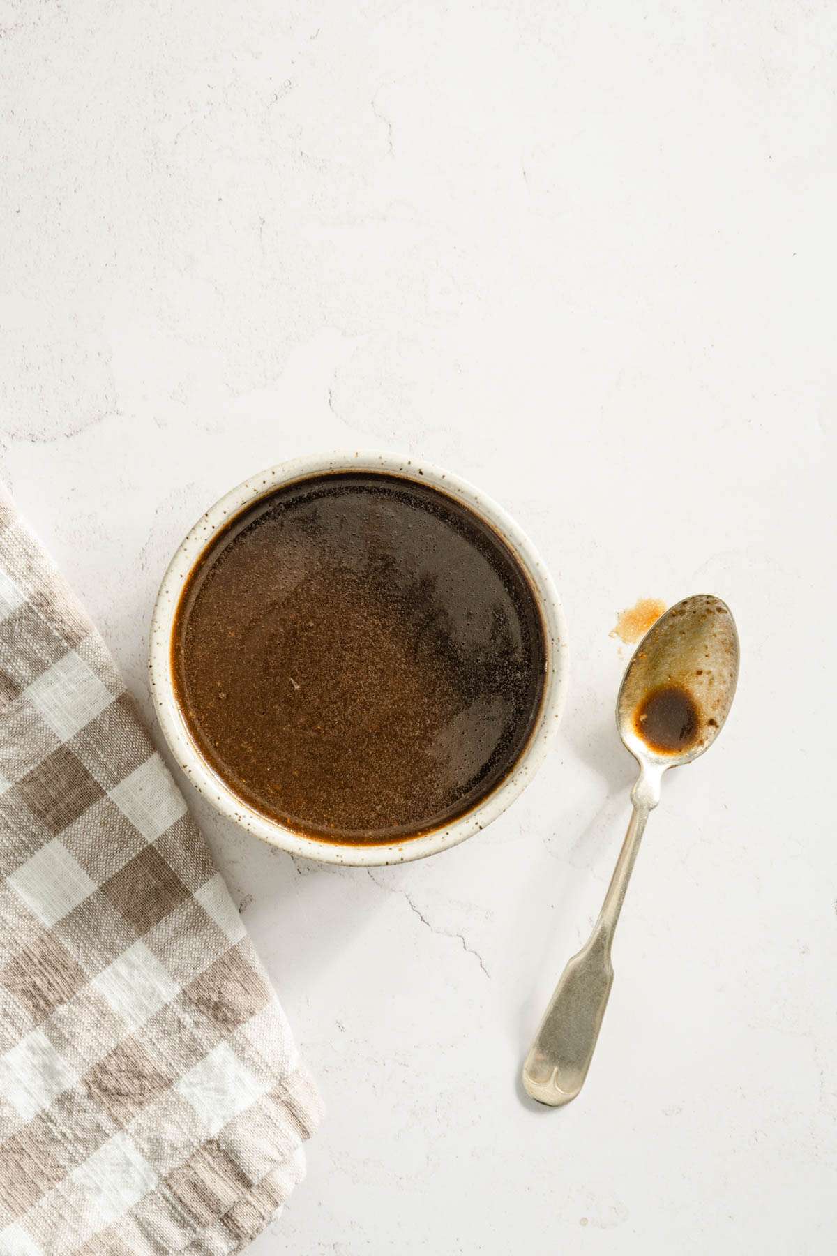 warm balsamic vinaigrette in a bowl, spoon, and napkin