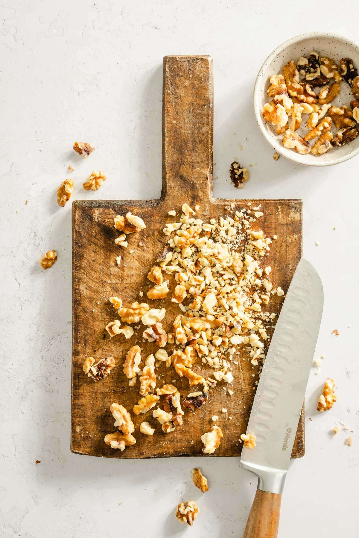 walnuts on a cutting board, small dish with whole walnuts, cutting knife