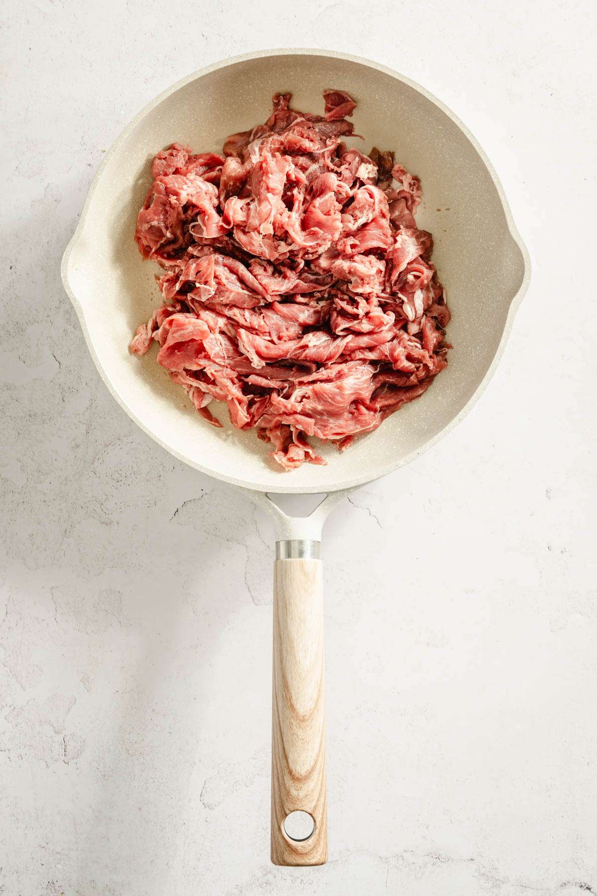 raw shaved beef on a frying pan