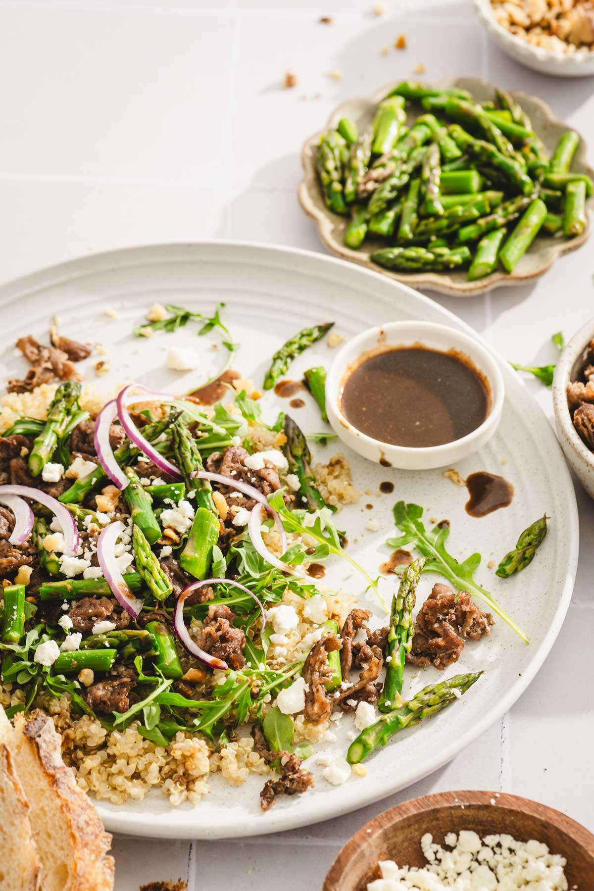 close up of plate with the salad, dish with dressing and cut up asparagus