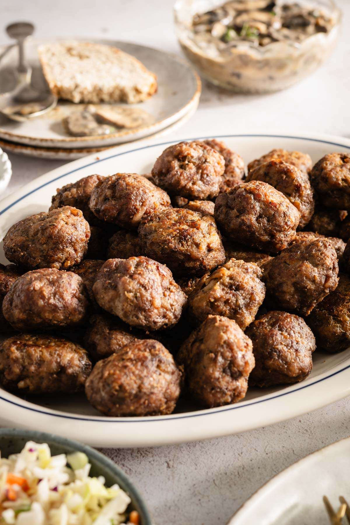 Meatballs on a serving platter; small side dishes around, close up