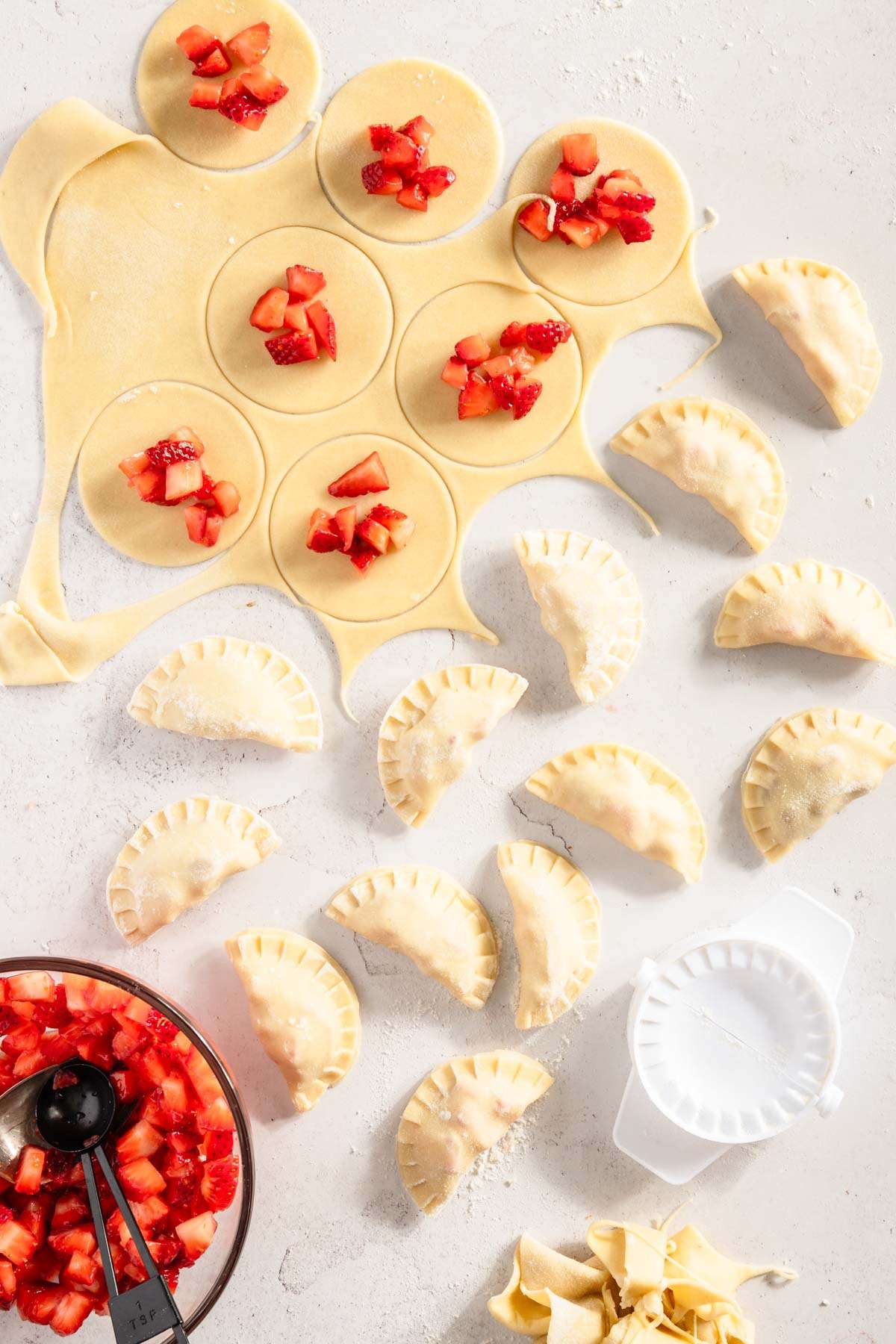 pierogi dough rolled out, circles cut, some made pierogis; bowl with the strawberry filling