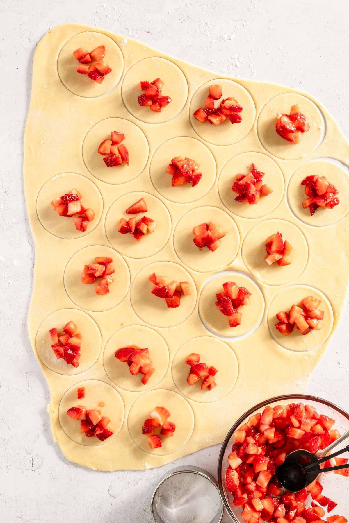 rolled out dough with cut out circles, strawberry filling placed on the circles