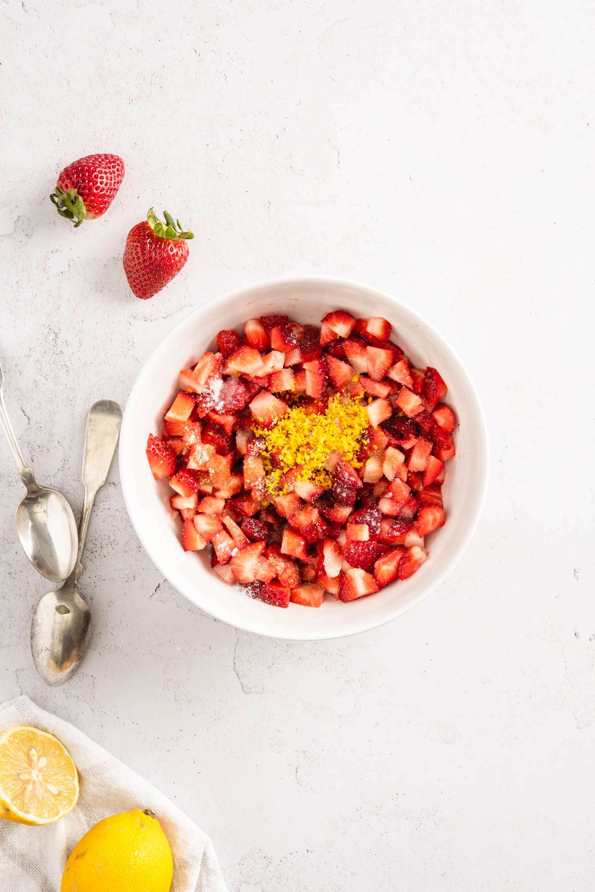 bowl with cut up berries with lemon zest, vanilla, sugar and lemon juice added on top