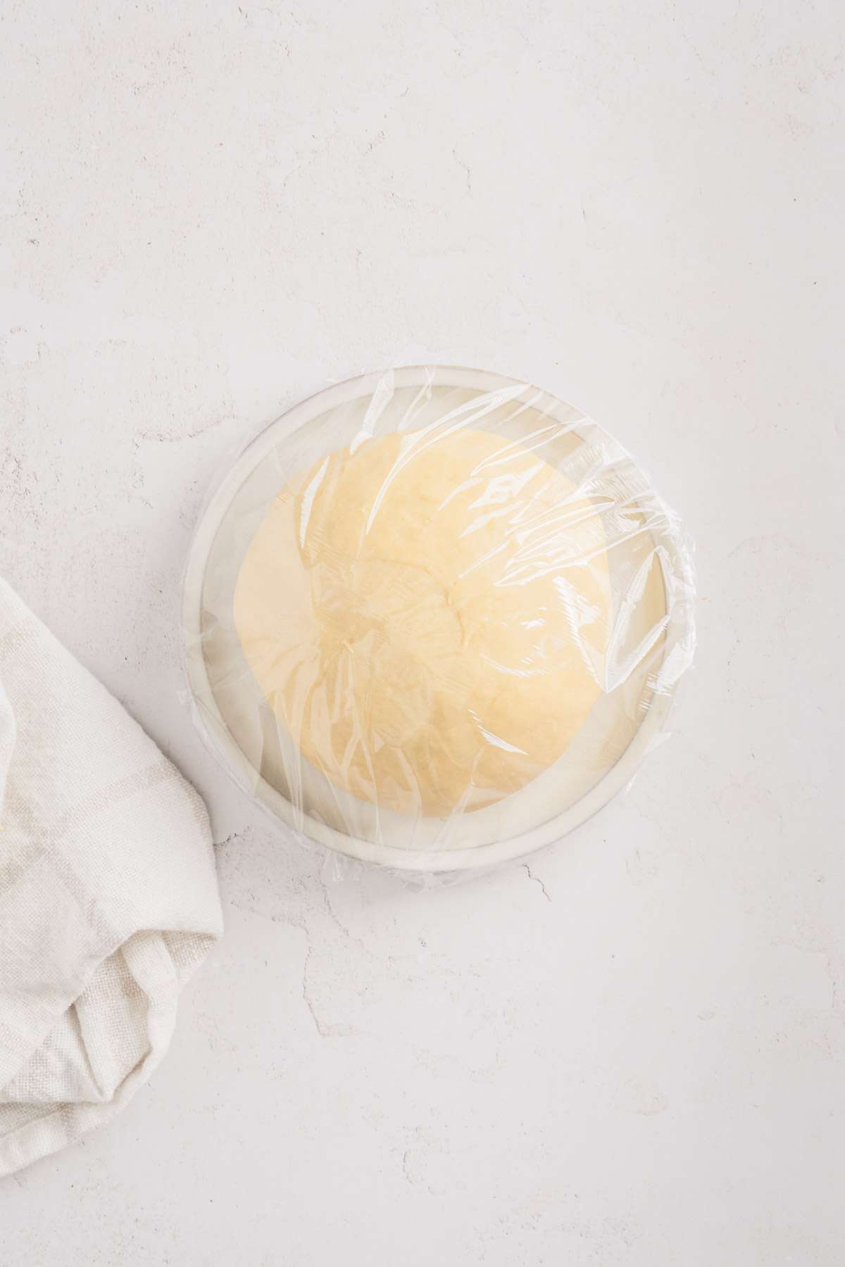 formed dough on a plate, wrapped in a plastic wrap