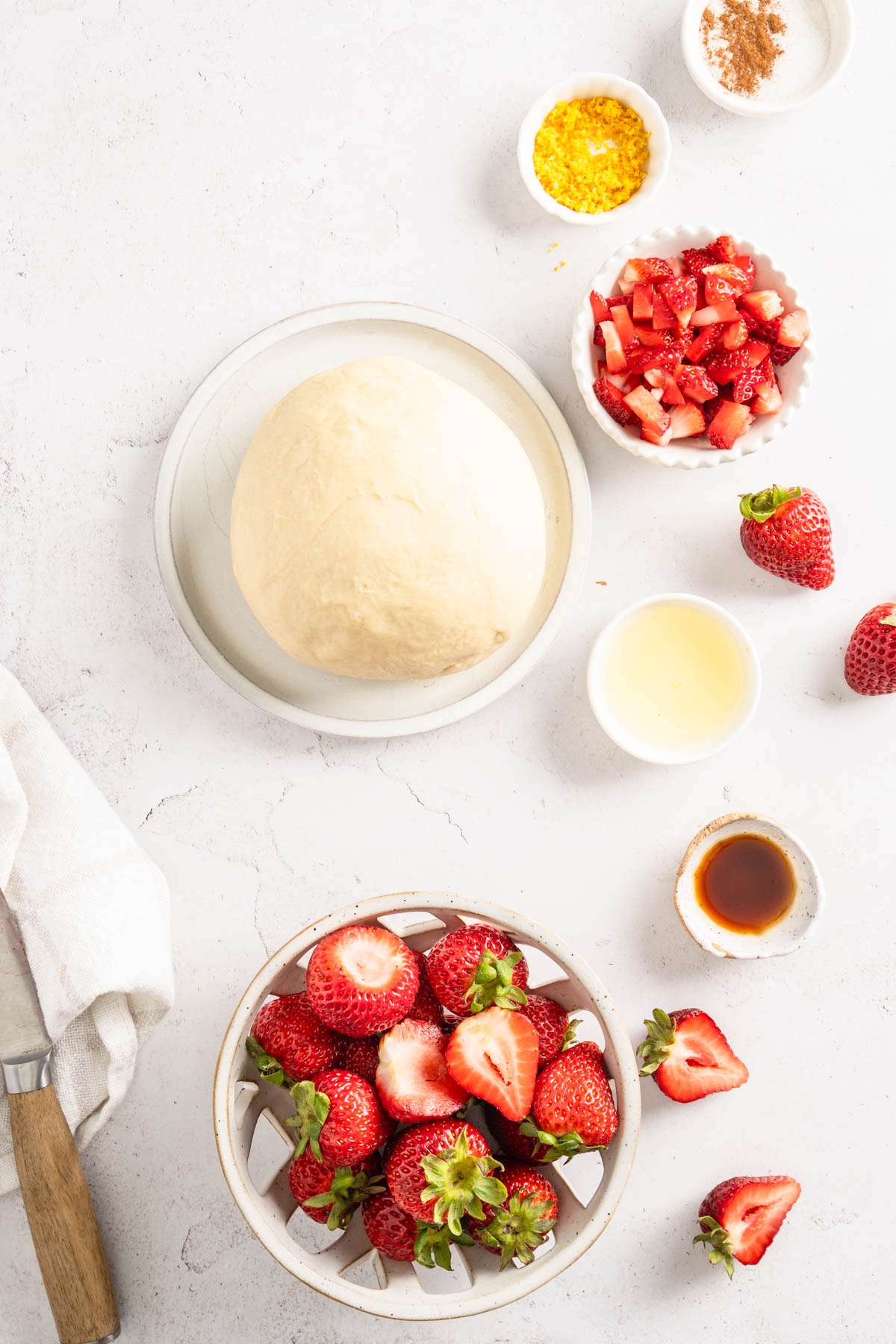 formed pierogi dough in a small plate, dish with strawberries, lemon juice and vanilla