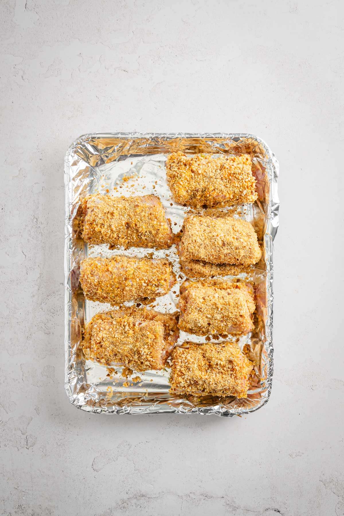 stuffed pork chops ready for frying, on a baking sheet