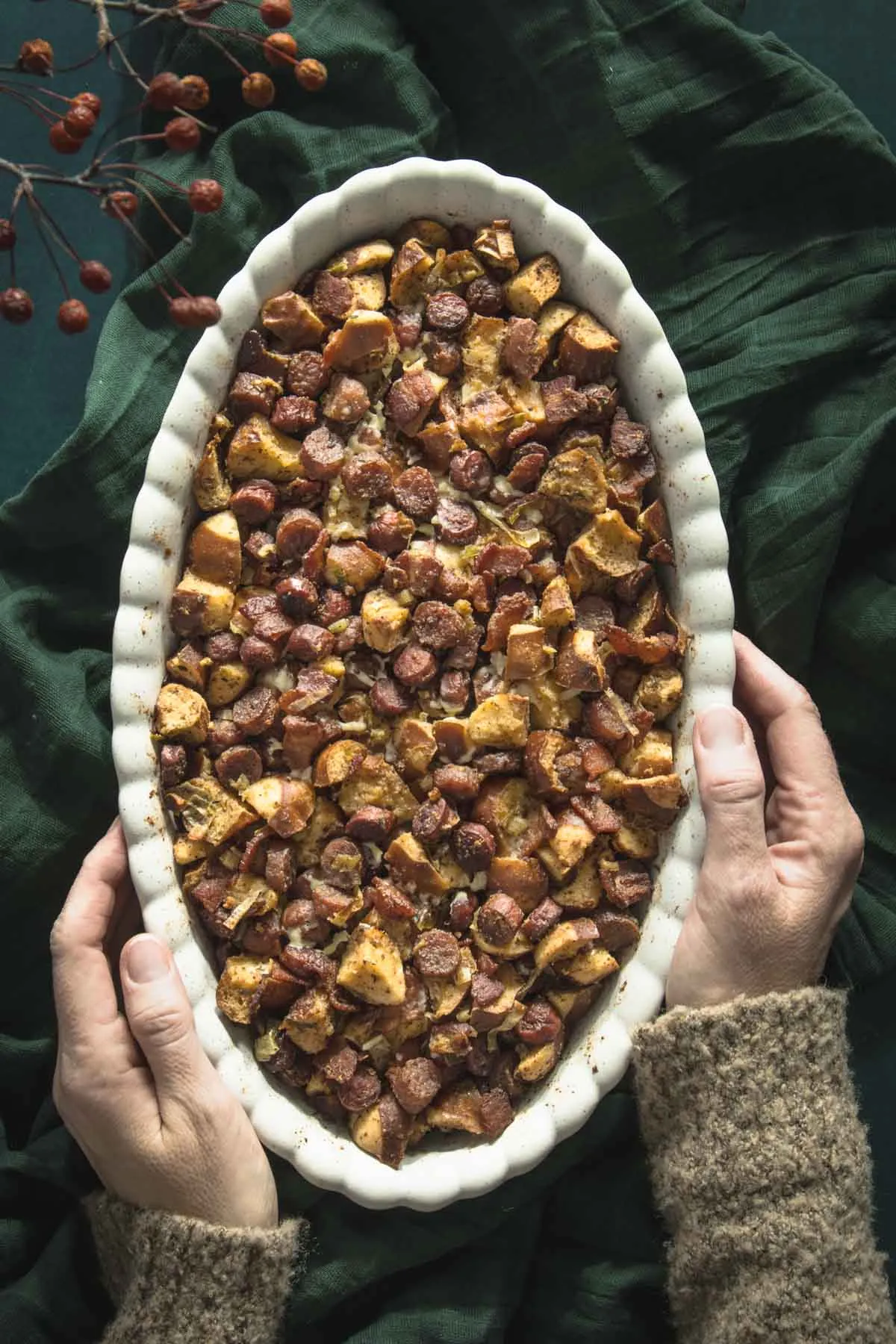 cooked stuffing in an oval dish, hands holding the dish