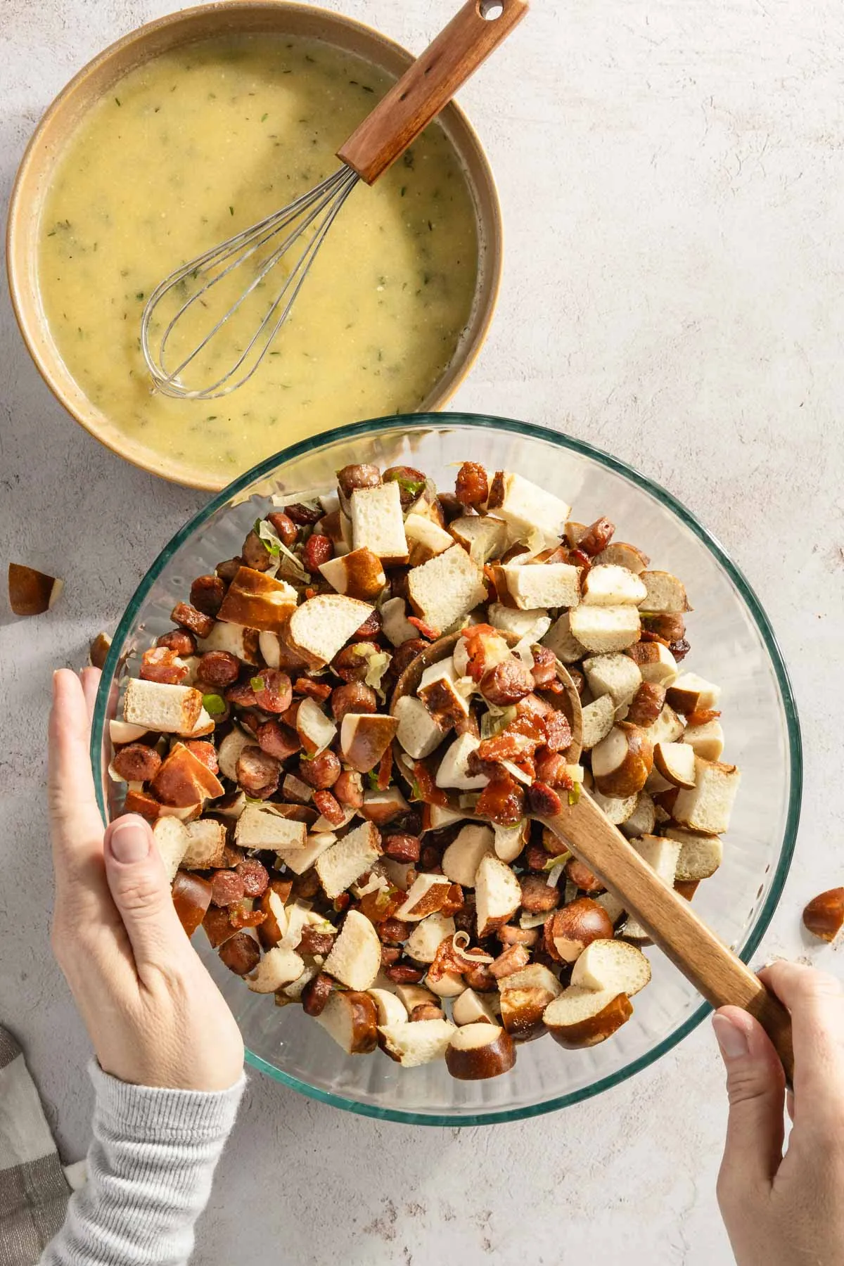 hands mixing the pretzels with the three meats using large spoon
