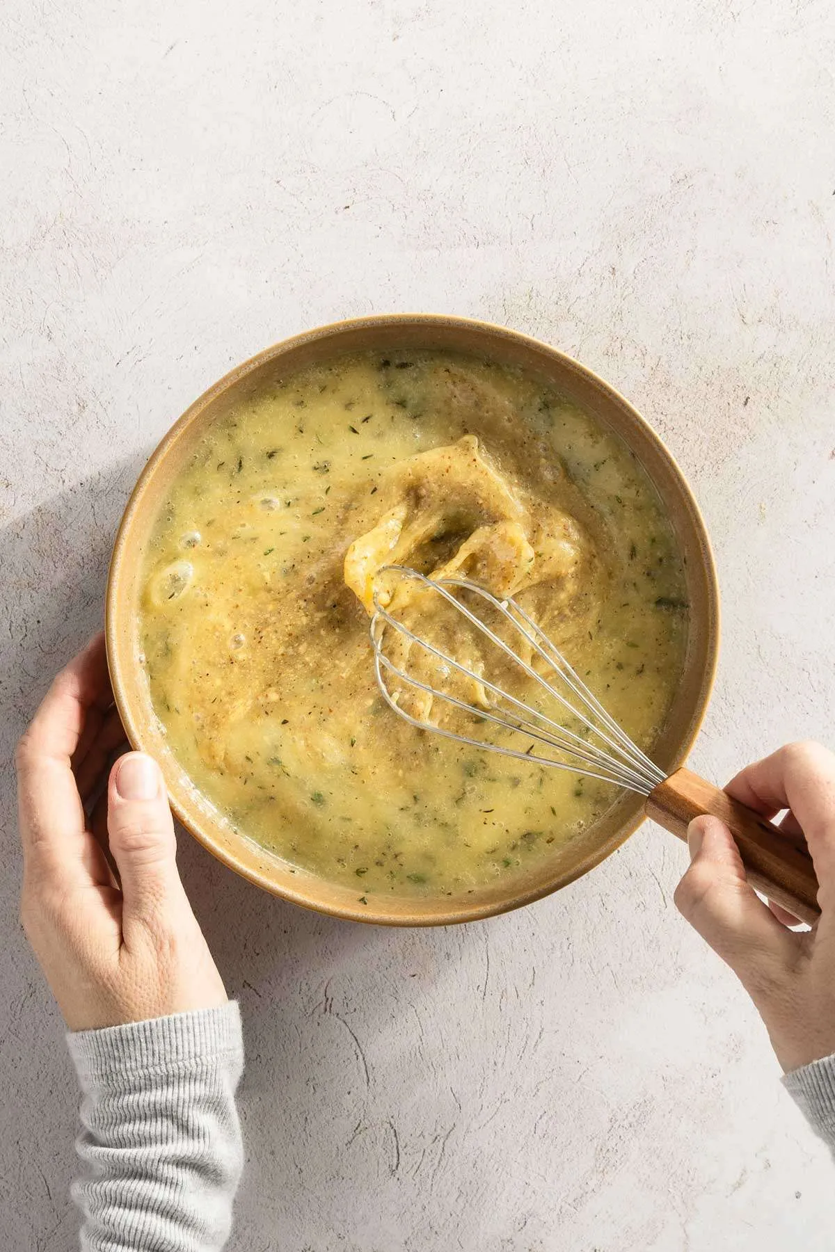 hand holding whisk, mixing the sauce